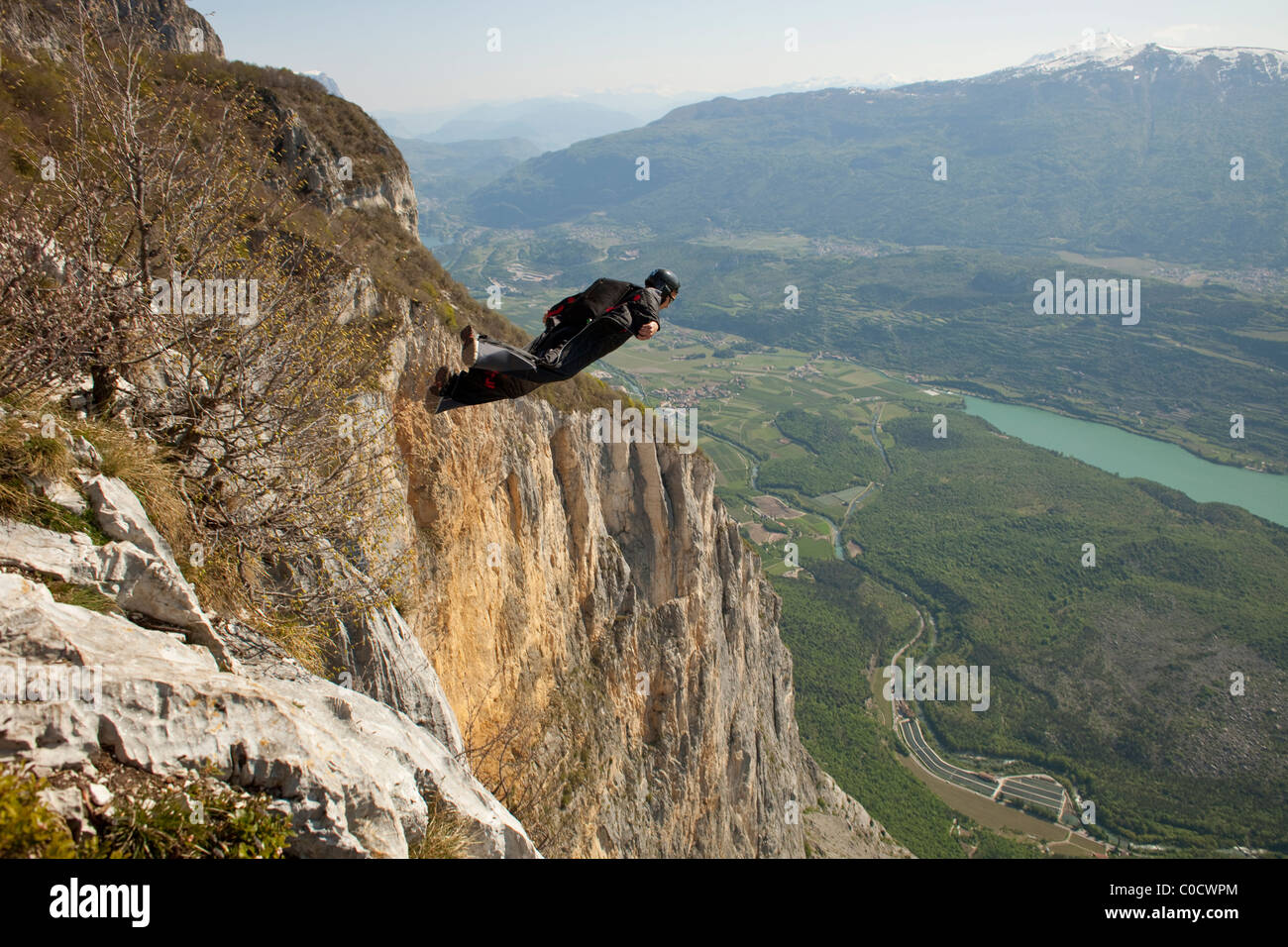 BASE Taucher in einem Wingsuit springt von Klippe und fliegt nach unten ins Tal. Stockfoto