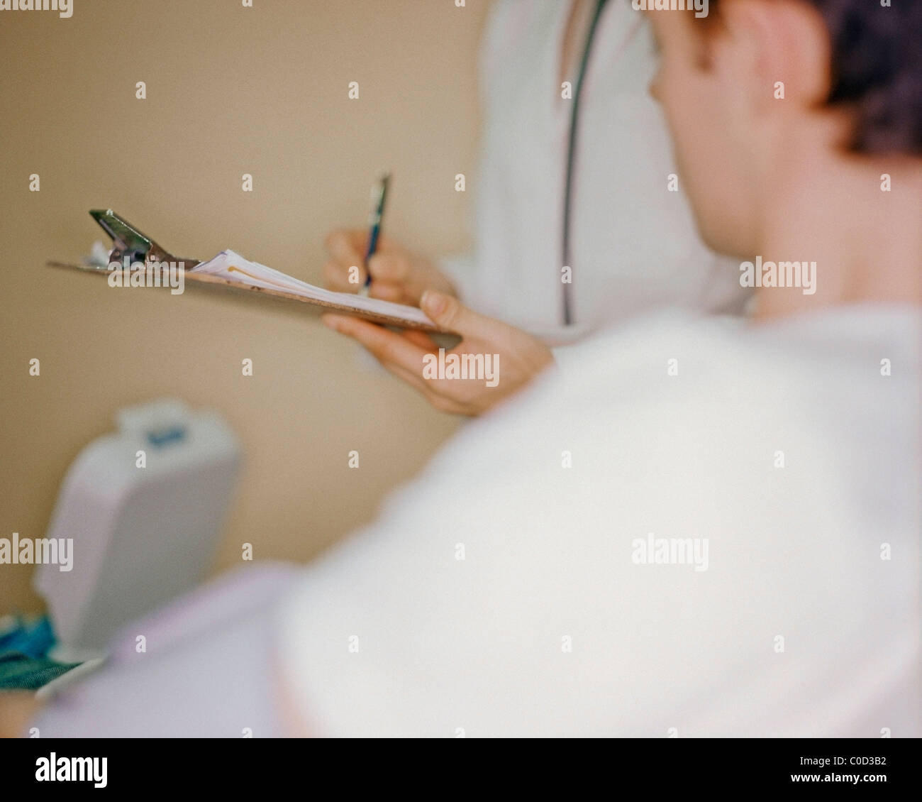 Medical staff writing notes as patient has blood pressure taken Stockfoto