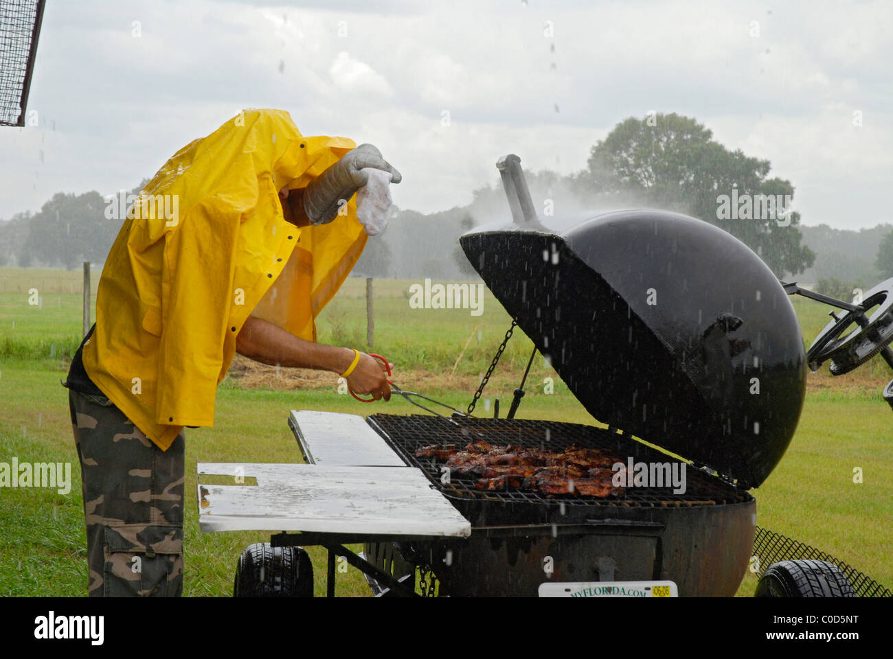 Mann Grillen Huhn im Regen Florida Stockfoto