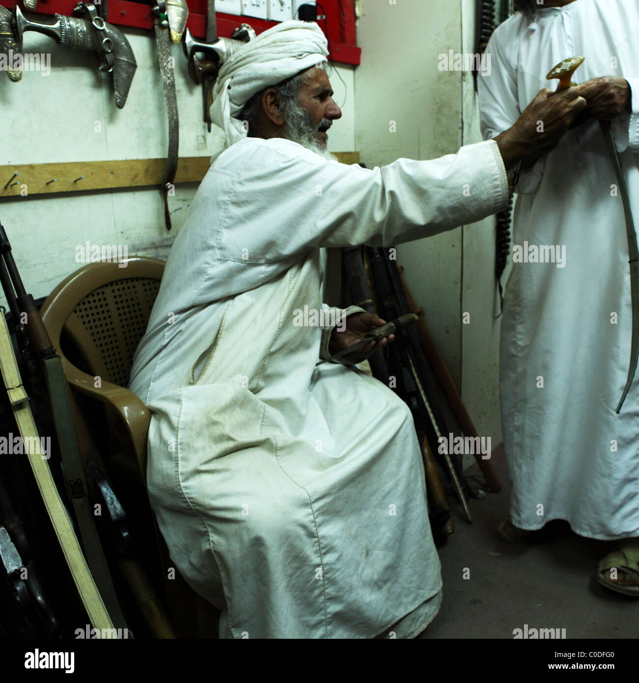 Ein omanischer Mann sitzt in einem Waffen-Shop in der indoor Souk (Markt) von Nizwa, Oman. Stockfoto