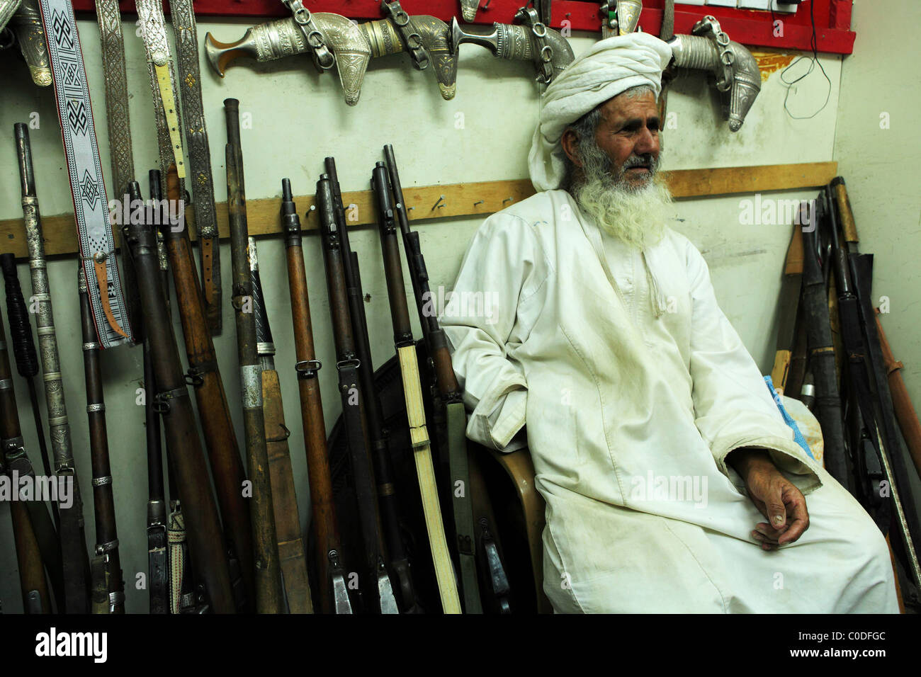 Ein omanischer Mann sitzt in einem Waffen-Shop in der indoor Souk (Markt) von Nizwa, Oman. Stockfoto