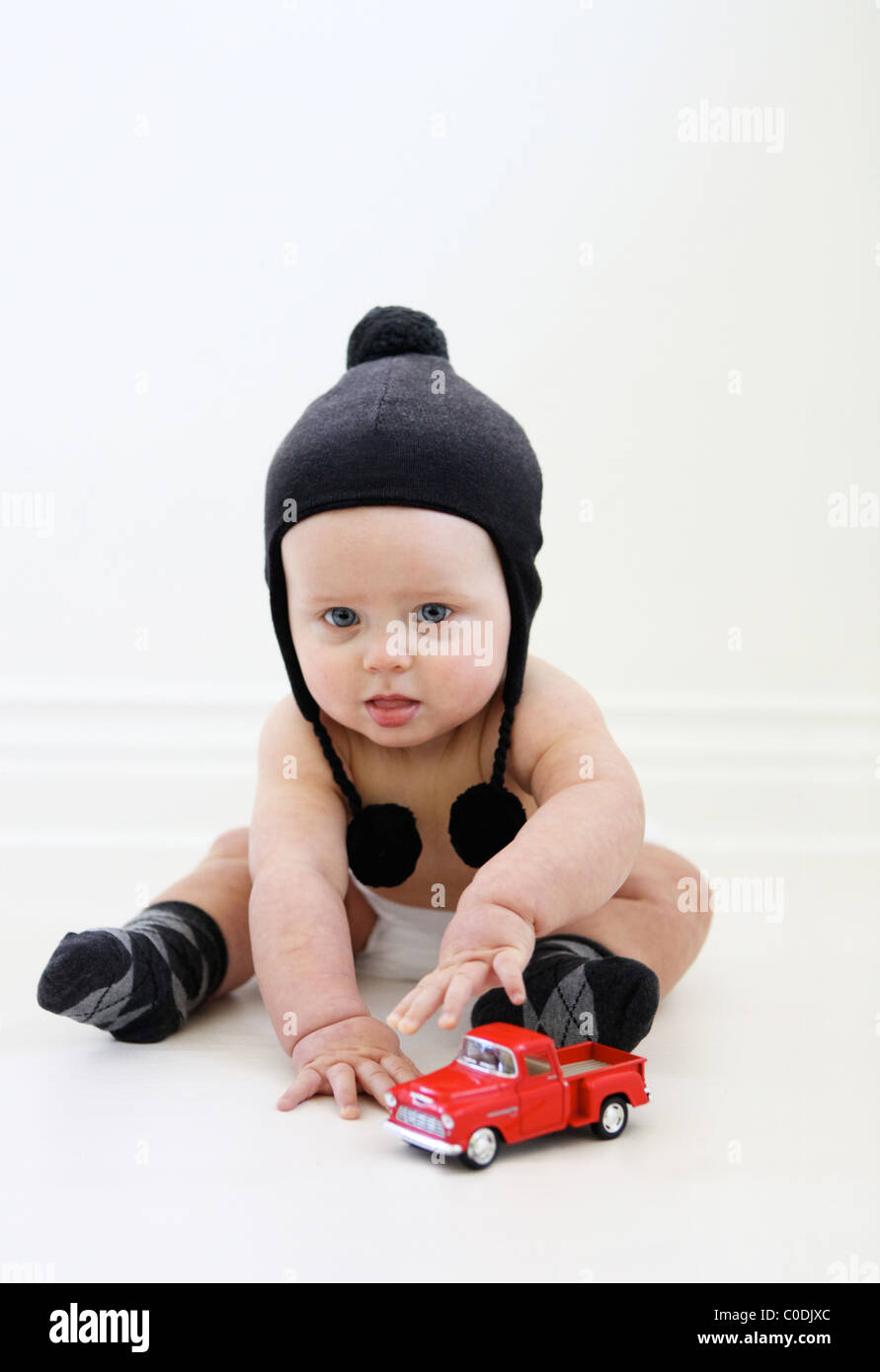 Baby Boy in Windel und Winter Hut mit einem LKW spielen Stockfoto
