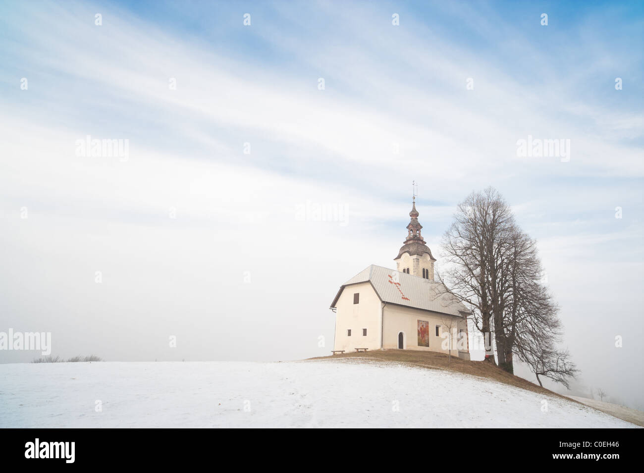 Kleine Kirche auf verschneiten Hügel. Slowenien, Skofja Loka Bereich, St. Andrej Church. Stockfoto