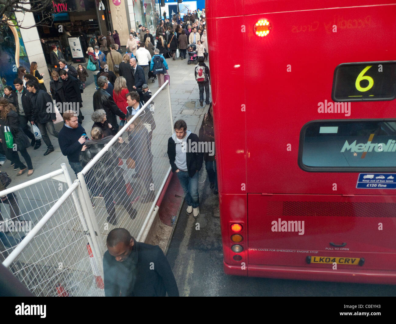 Shopper Fußgänger zu Fuß auf der Straße zwischen einem Doppeldecker-Bus und eine Crossrail Barriere Oxford Street London England UK Stockfoto