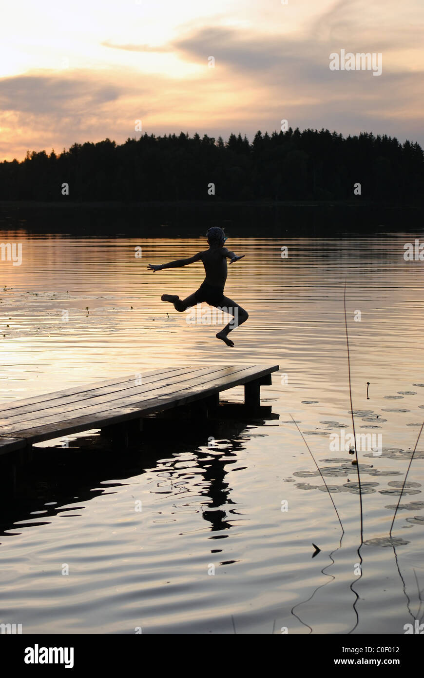 Junge springt ins Wasser vom pier Stockfoto
