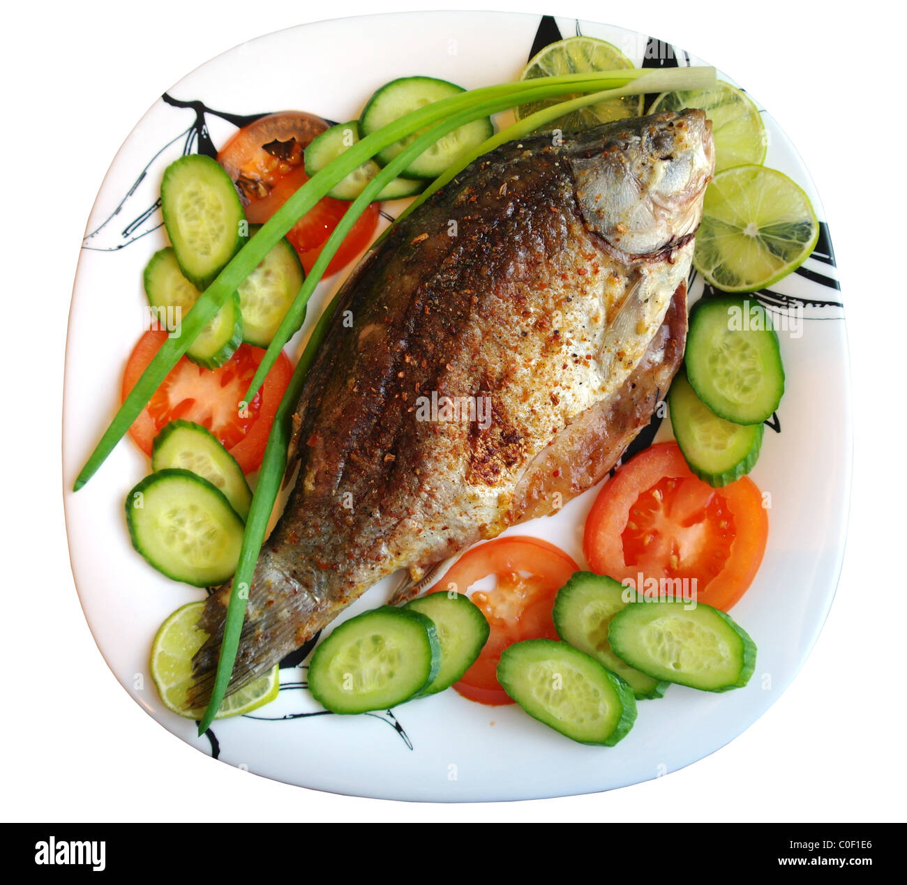 Gebratener Fisch Karausche auf einem Teller mit Tomaten, Gurken, Zwiebeln und Kalk, wird isoliert, einen weißen Hintergrund Stockfoto