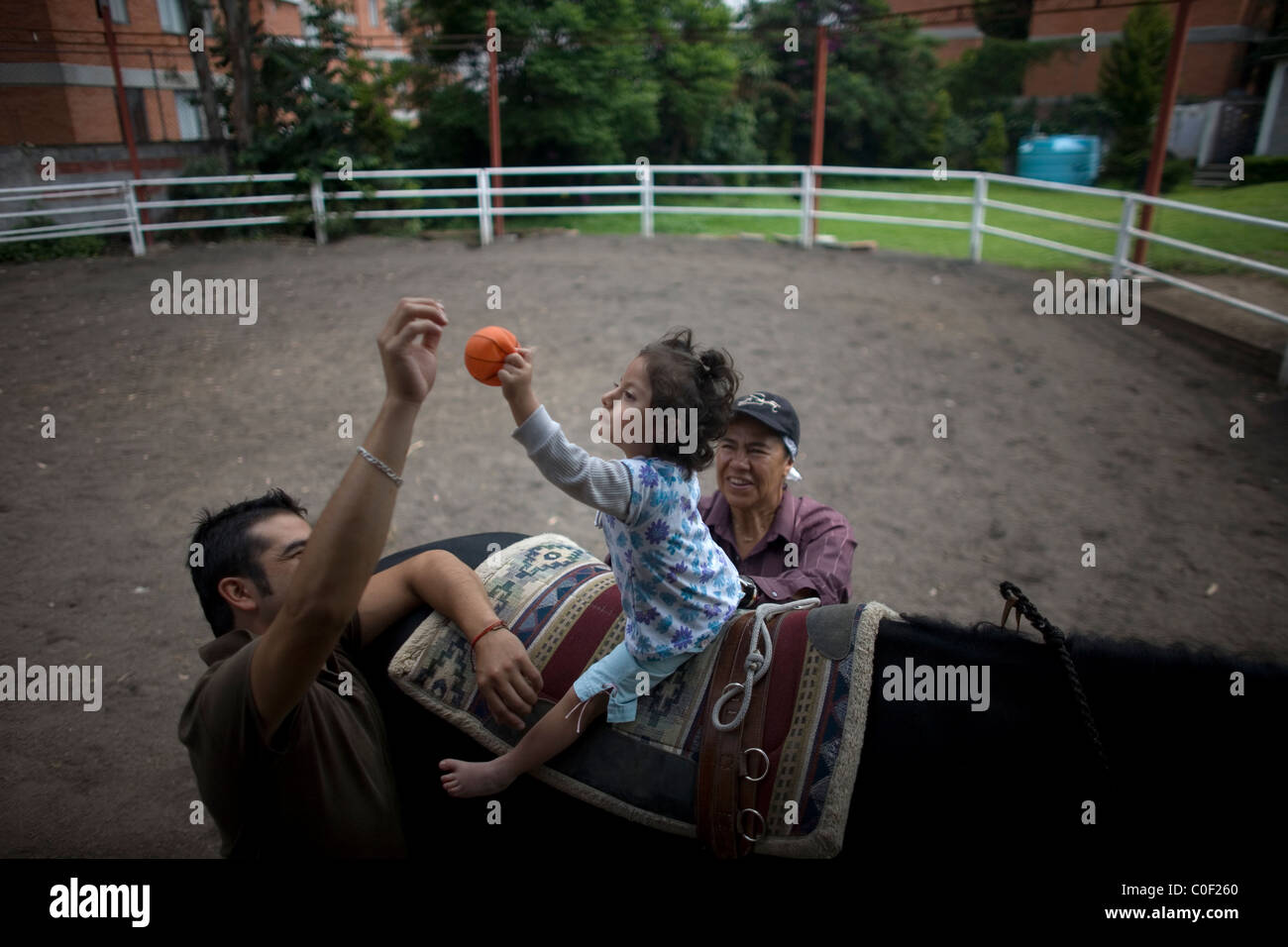 Eine Mädchen, die infantile zerebrale Lähmung und angeborene Fehlbildung leidet, erreicht für einen Ball, wie sie auf der Rückseite ein Hors sitzt Stockfoto
