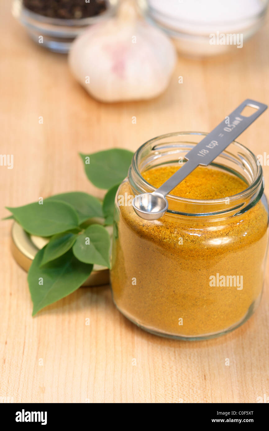 Curry-Pulver auf feine Holz Schneidebrett mit grobem Salz, Knoblauch, Pfeffer und Messlöffel Stockfoto