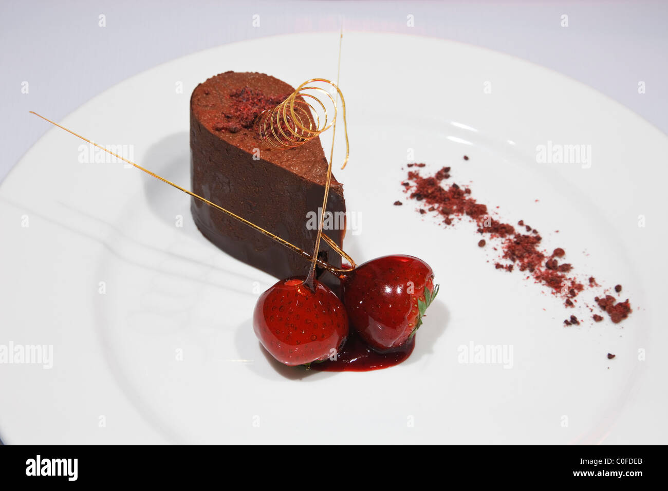 Schokoladenmousse mit zwei Erdbeeren Gourmet-Dessert Kurs auf einem weißen Teller von oben Stockfoto