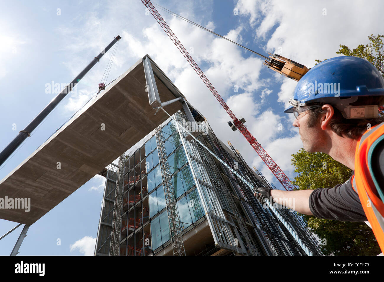 Betreiber halten Seile Kran heben auf Baustelle zu führen. Stockfoto