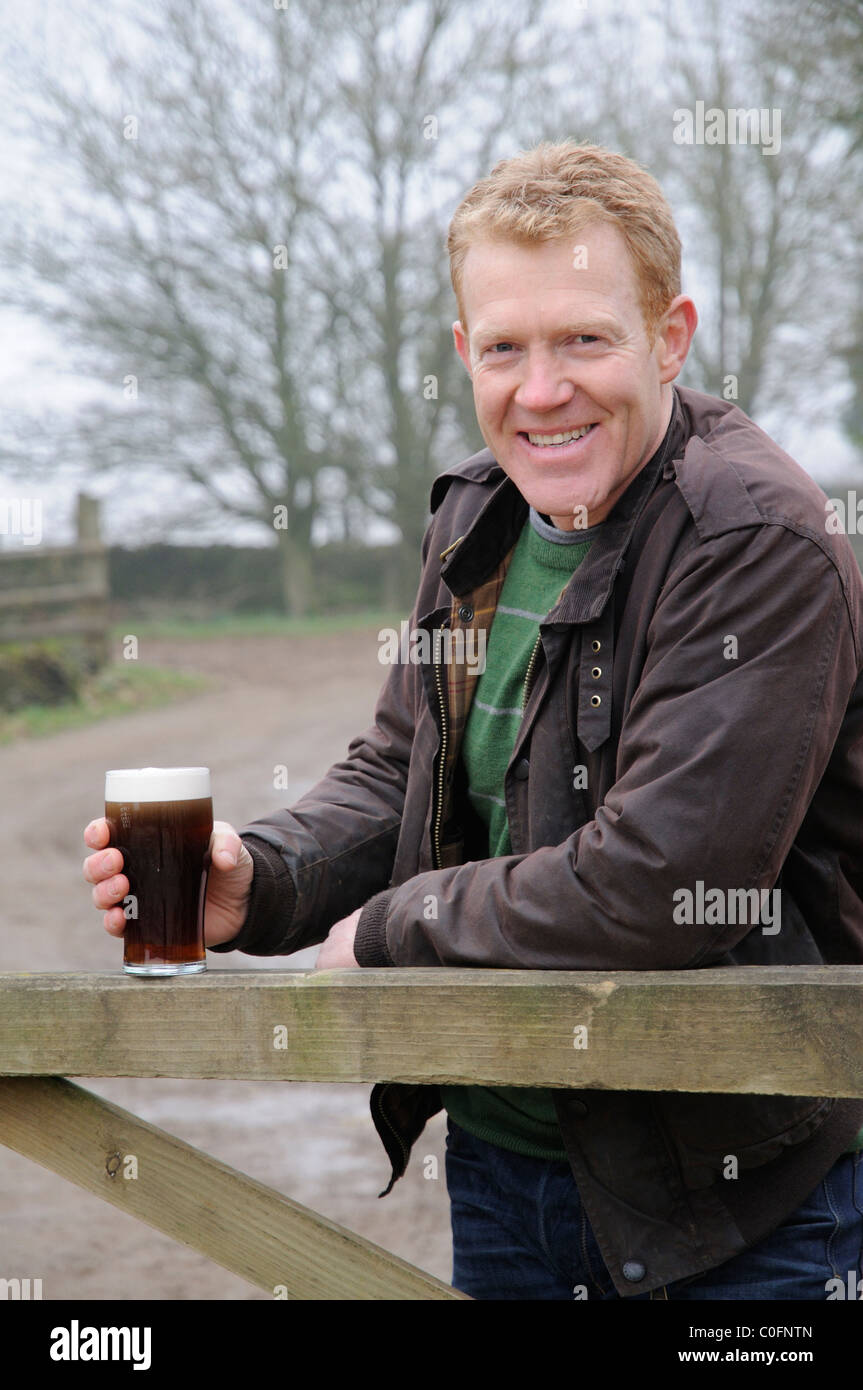 Halten Sie ein Glas Bier, Adam Henson Landwirt und Fernsehmoderator zu Hause auf seiner Farm in den Cotswolds Gloucestershire, England Stockfoto