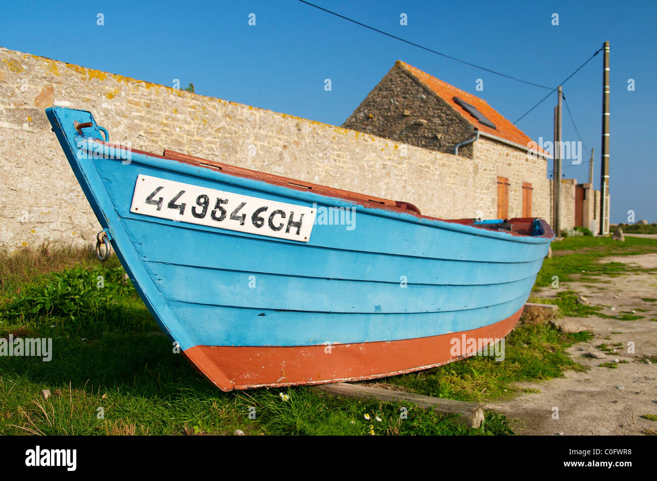 Blaue Fischerboot vor einer Steinmauer in Gatteville-le-Phare an der Pointe de Barfleur. Stockfoto
