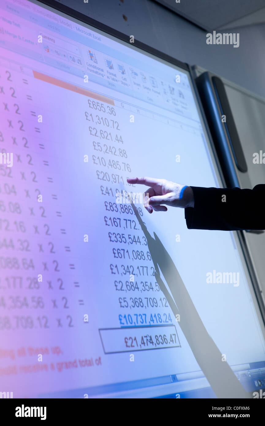 Ein Mann präsentiert eine Tabelle mit finanziellen Zahlen über ein interaktives digitales Whiteboard UK Stockfoto