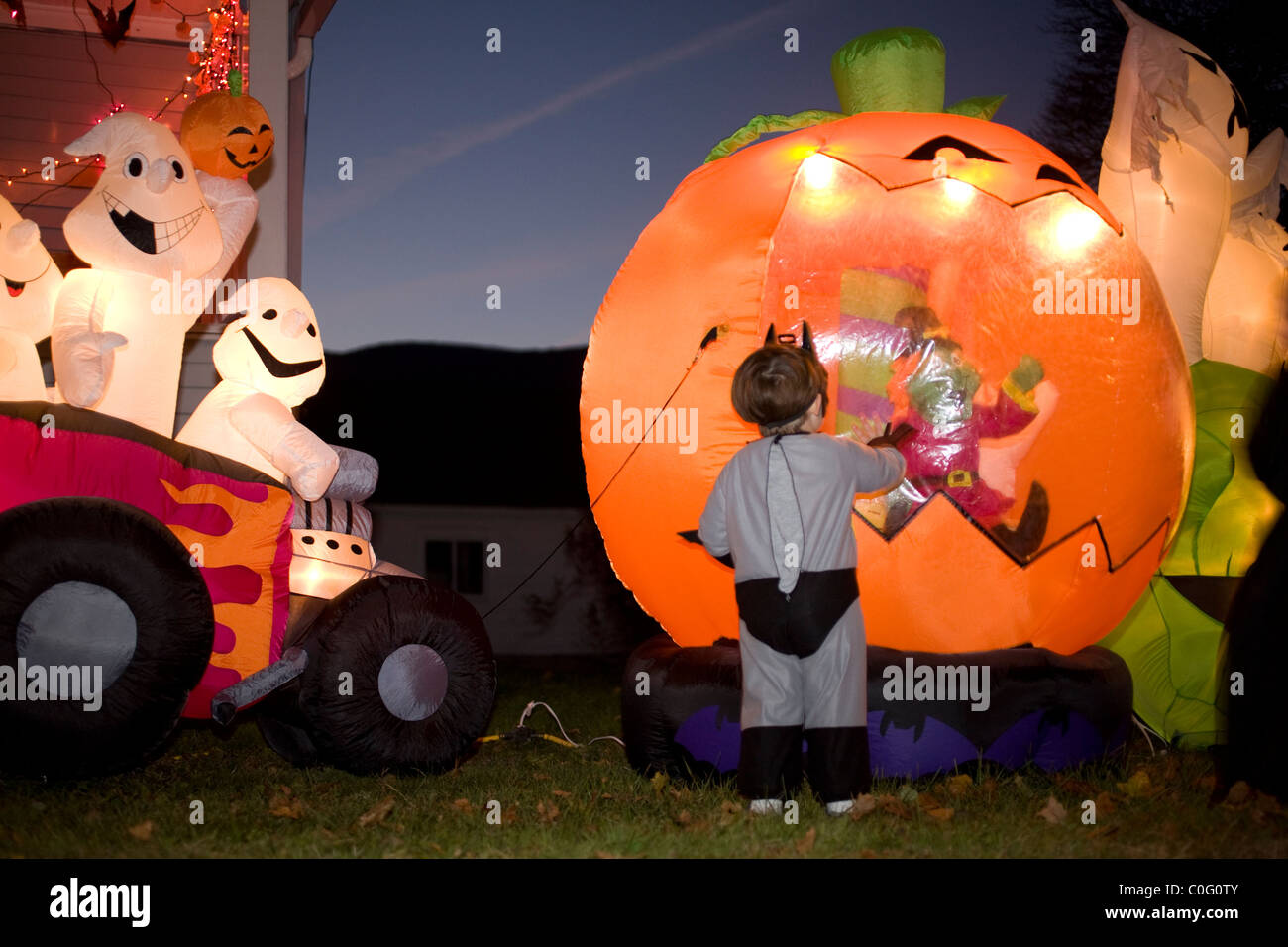 Buntere beleuchtete aufblasbare Dekorationen faszinieren einen kleinen junge an Halloween Stockfoto