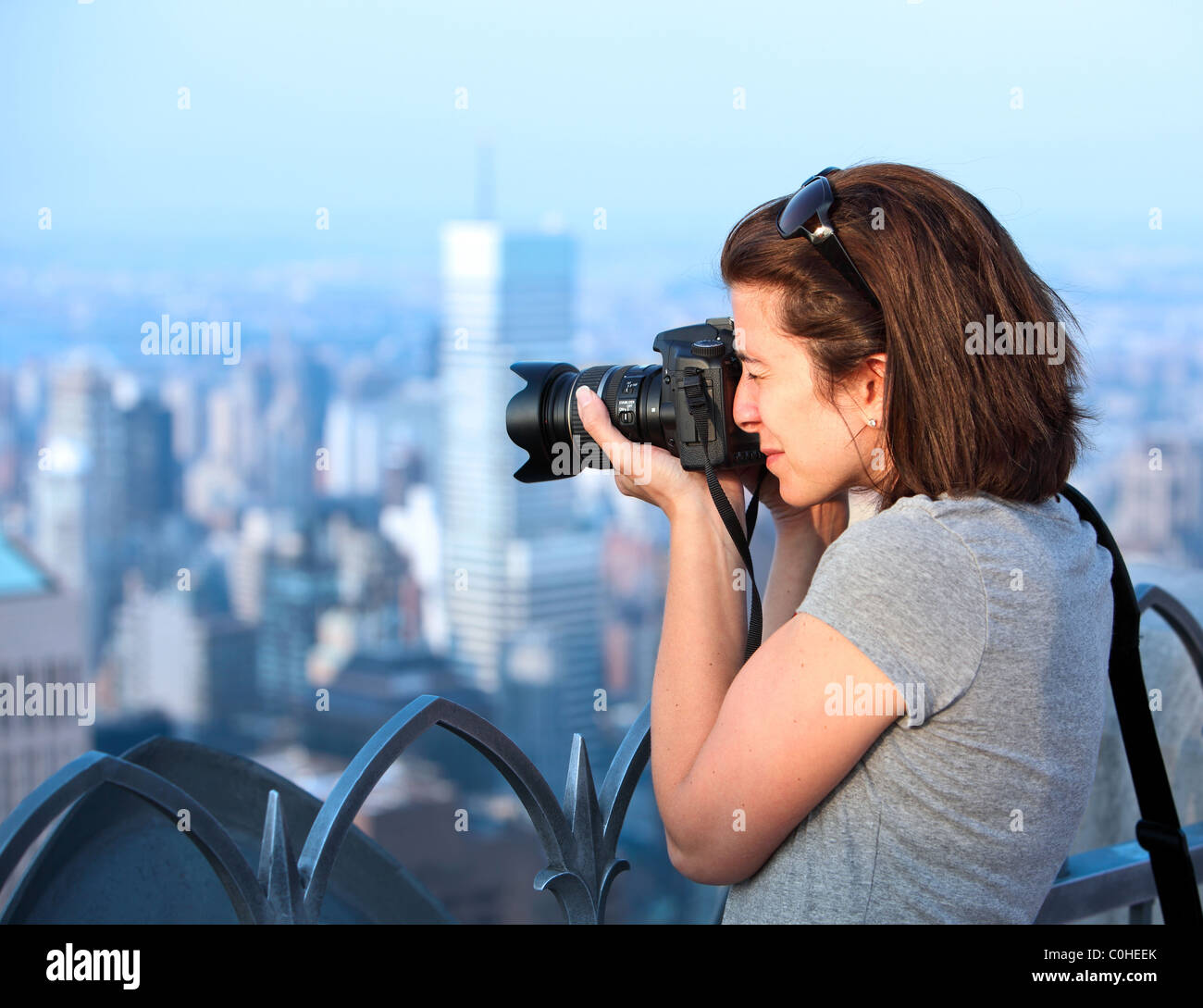 Attraktive weibliche Fotografin bei Sonnenuntergang auf einem Wolkenkratzer Stockfoto