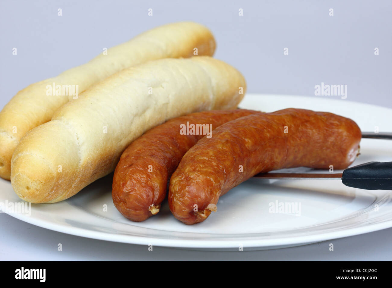 Zwei Schinken-Würstchen mit Brötchen auf einem Teller Stockfoto