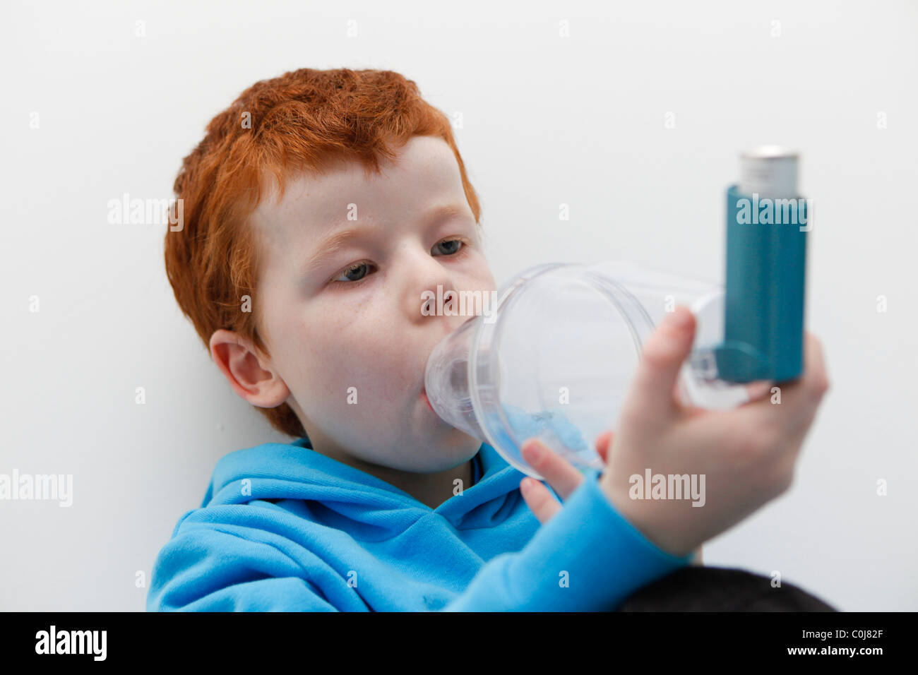 Kleiner Junge mit seinem Asthma-Inhalator um Symptome zu lindern. Stockfoto