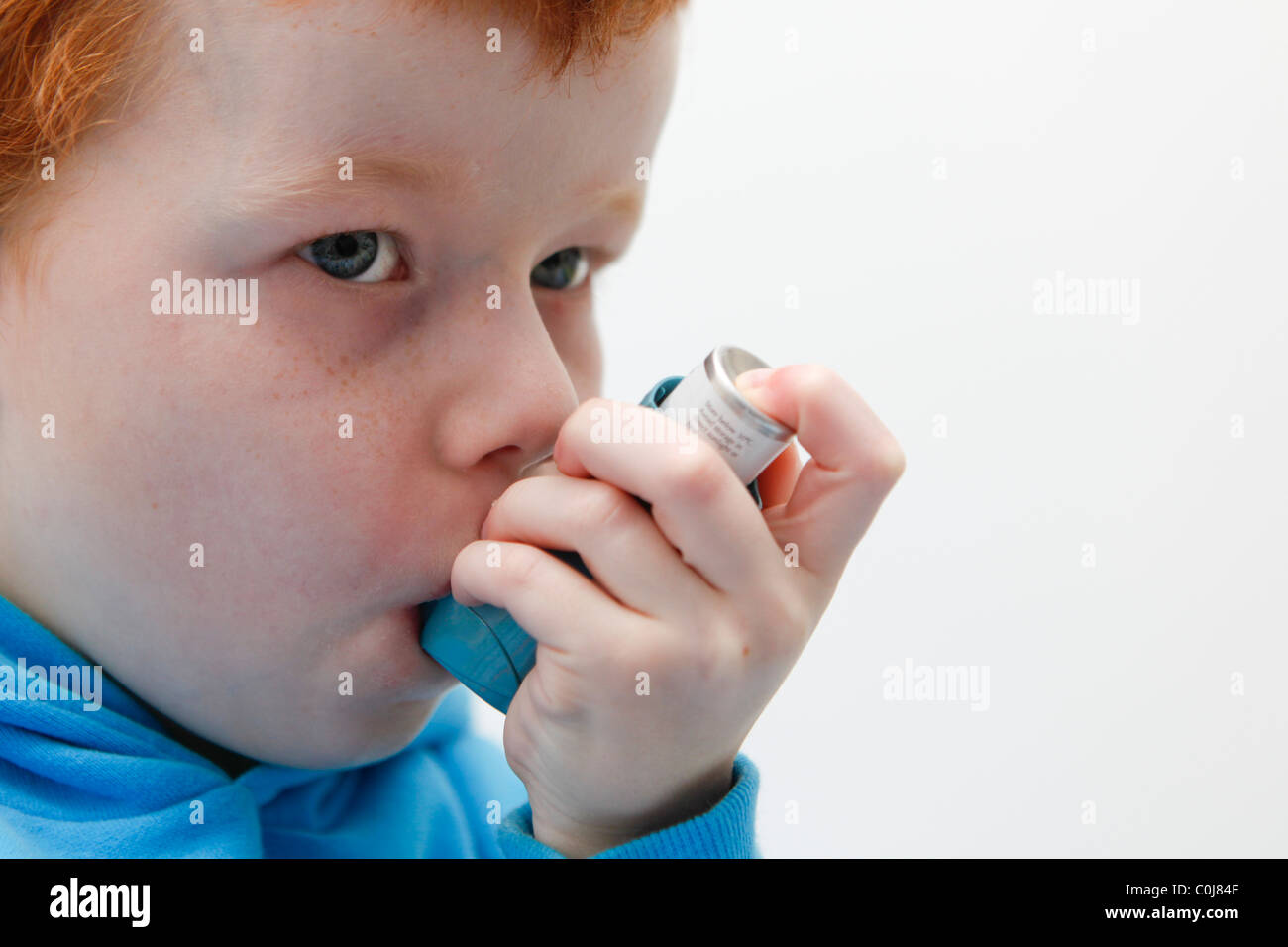 Kleiner Junge mit seinem Asthma-Inhalator um Symptome zu lindern. Stockfoto