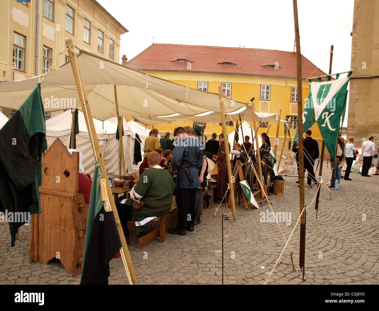 Menschen verkleidet als Ritter und Essen um einen hölzernen Mittelalterfest, Siebenbürgen, Sibiu, Rumänien Tisch. Stockfoto