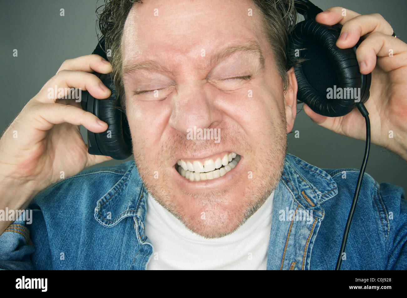 Schockiert Mann versucht verzweifelt, seine Kopfhörer abzunehmen. Stockfoto