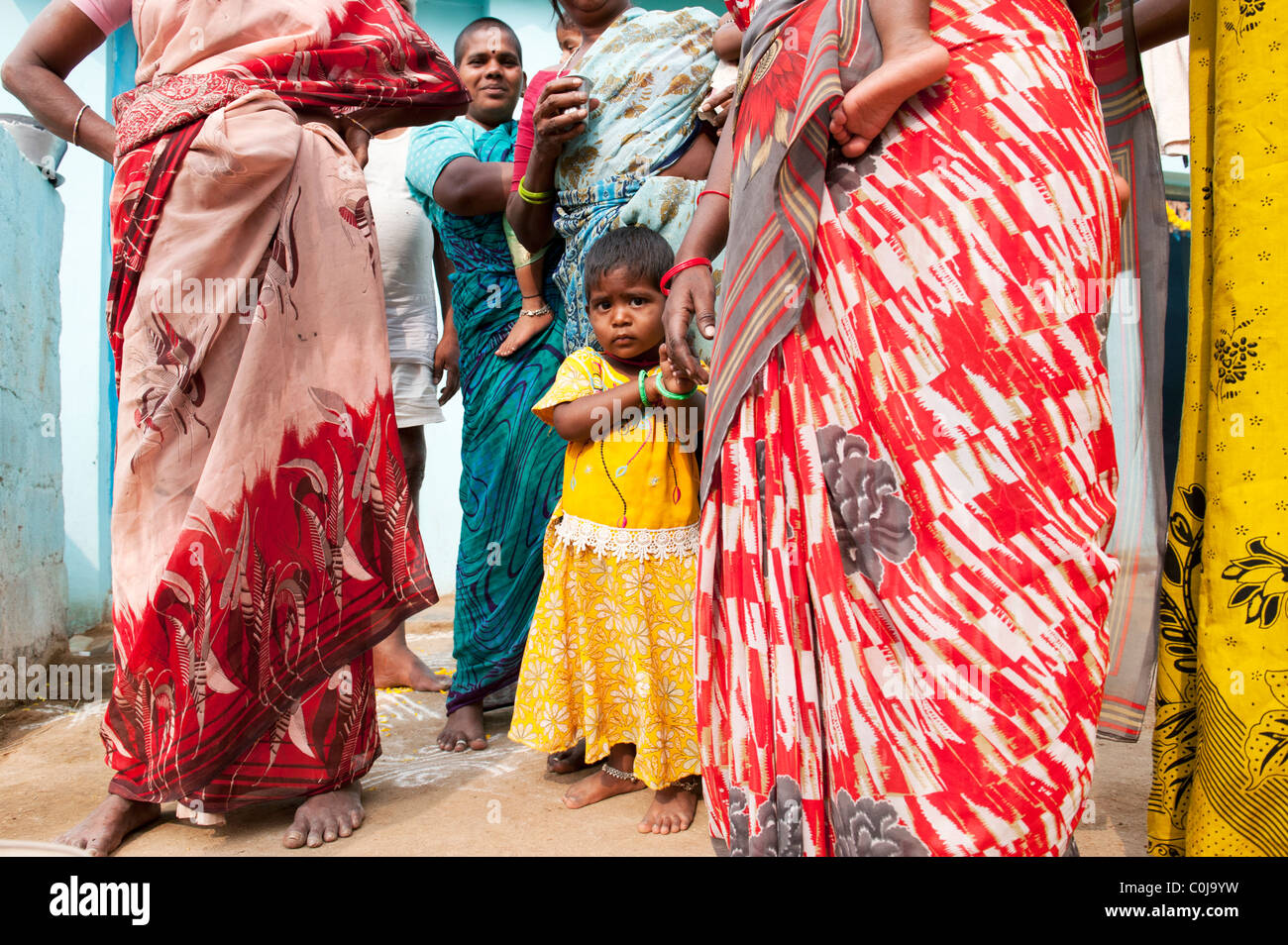 Kleine indische Mädchen stehen in zwischen indischen Frauen in einem indischen Dorf. Andhra Pradesh, Indien Stockfoto