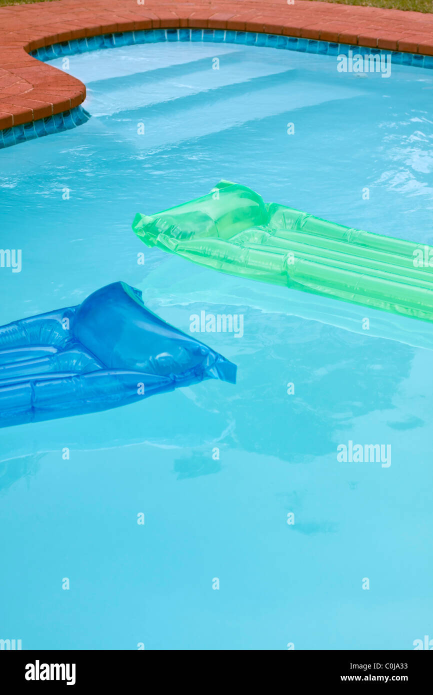 Schwimmbad mit zwei grünen und blauen Luftmatratzen. Stockfoto