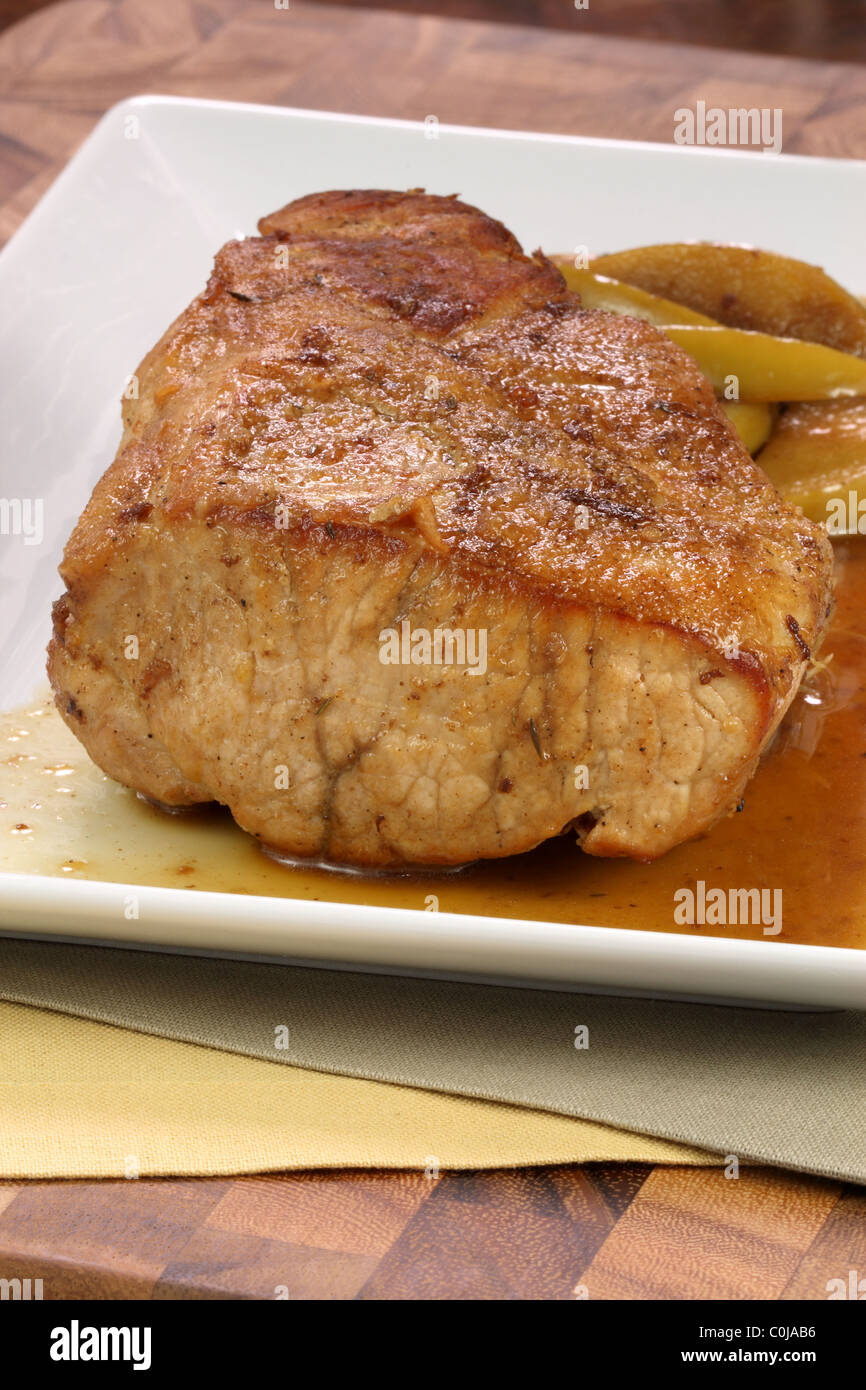feines Schweinefilet langsam gebraten mit frischen grünen Apfelspalten und Apfelmus Stockfoto