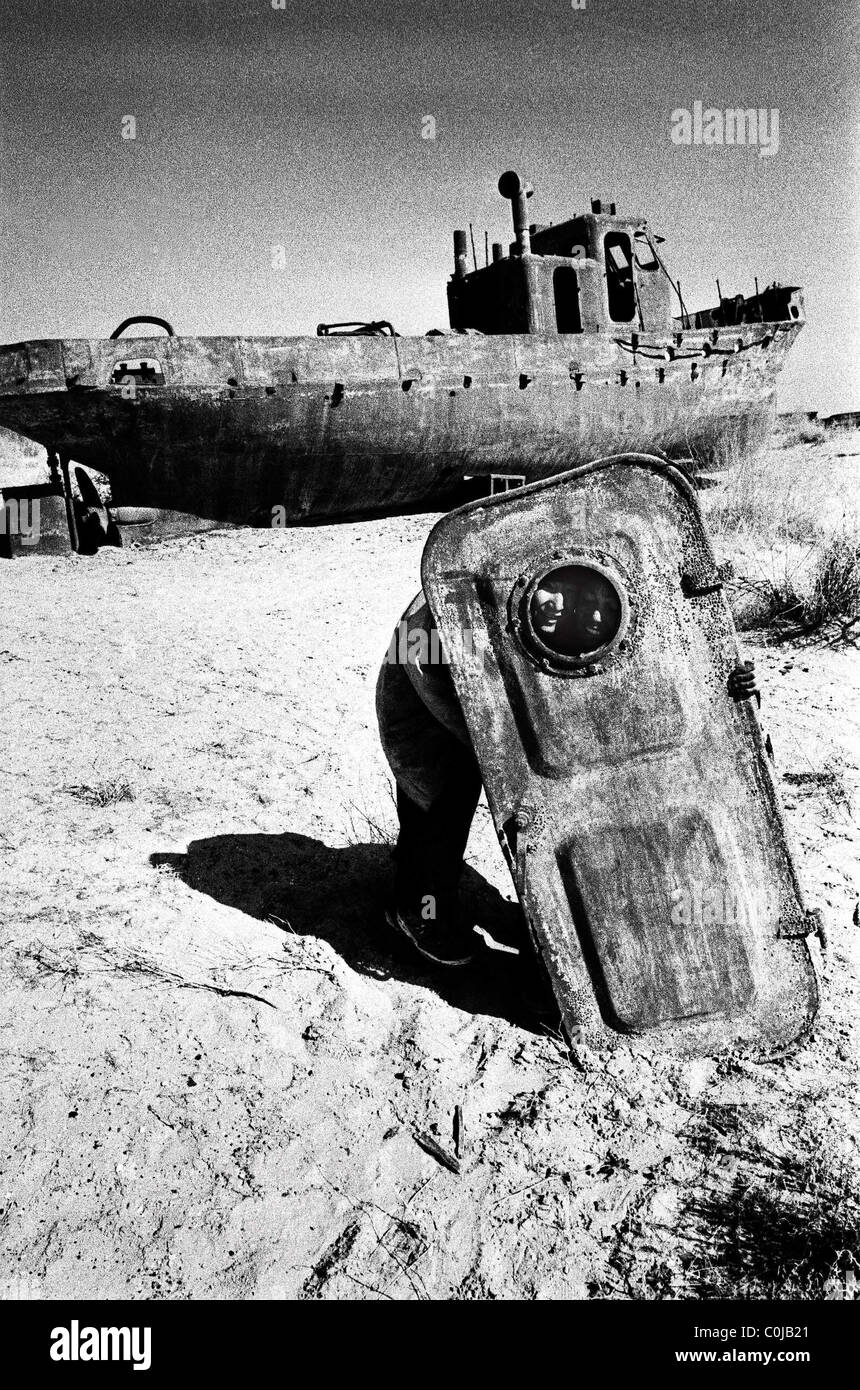 Moynaq, Usbekistan. Jungen spielen mit einer Tür aus einer alten Fischkutter hinterlassen die sich entfernenden Aral-See. Stockfoto