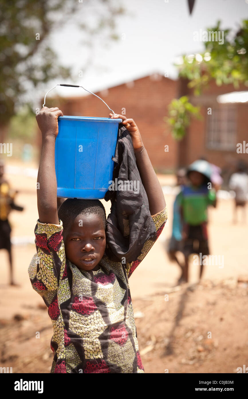Ein Kind führt das Wasser wieder aus einem Brunnen in Dedza, Malawi, Südafrika. Stockfoto