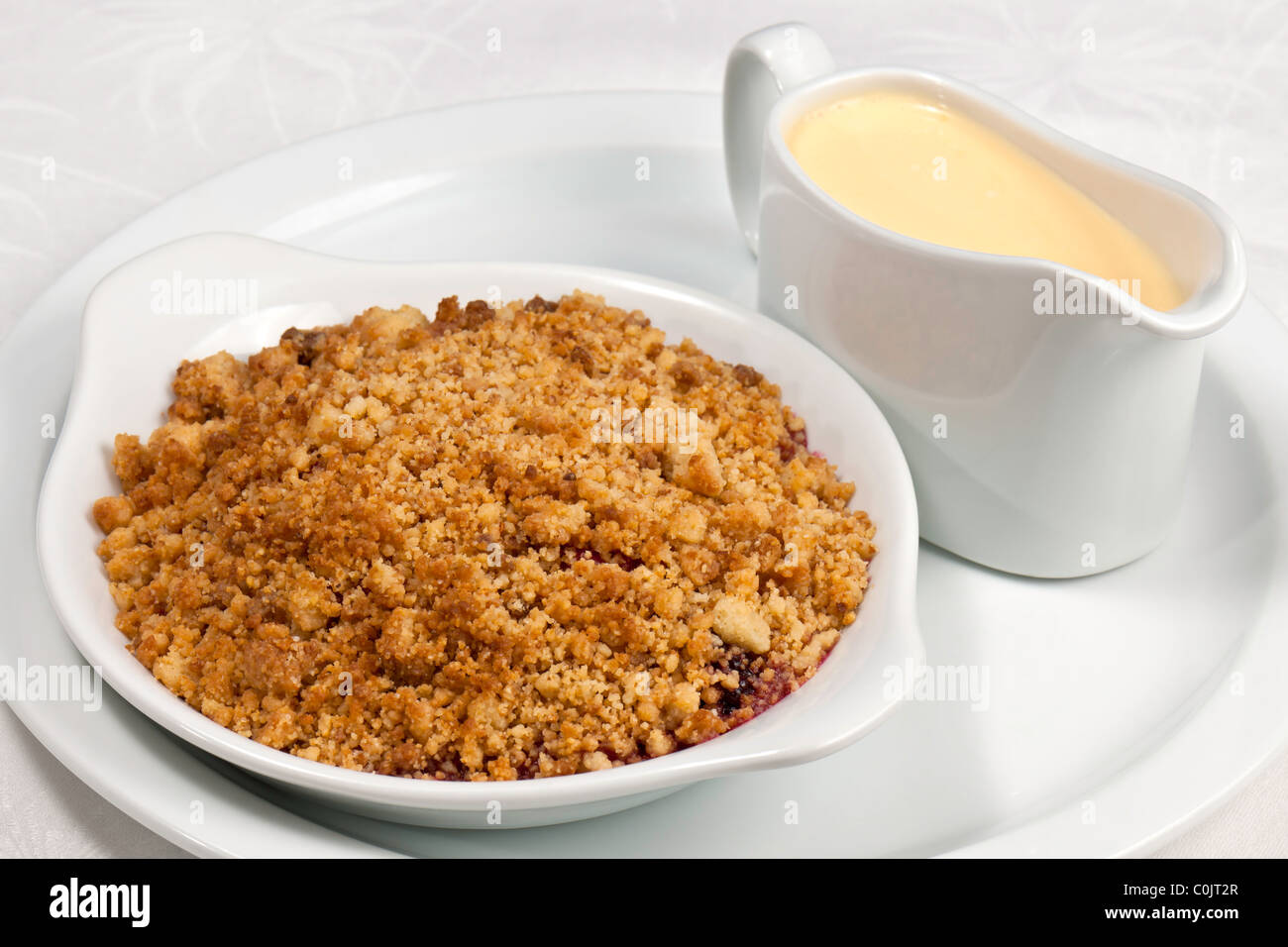 Kochs Präsentation Gericht - Apple und Blackberry crumble mit Vanillesauce. Stockfoto