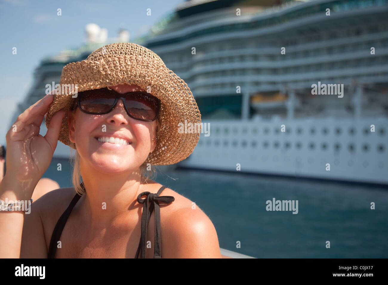 Lächelnde Urlaub Frau auf Tenderboot mit Kreuzfahrtschiff im Hintergrund. Stockfoto