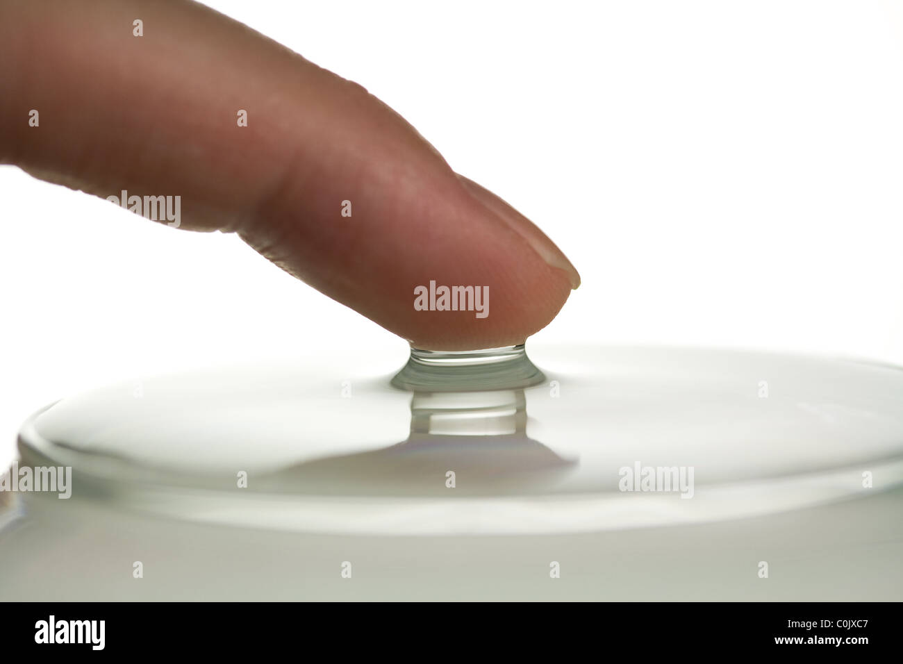 Finger, die Oberflächenspannung des Wassers zu demonstrieren Stockfoto