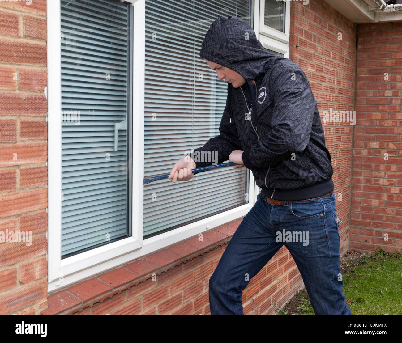 ein Mann versucht zu erzwingen, öffnen Sie ein Fenster auf einem Haus Stockfoto