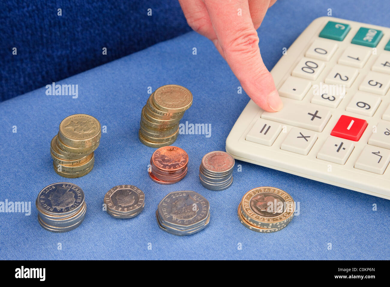 Person zählen Stapel des Englischen Pfund Münzen mit einem Rechner Geld GBP zu zählen. England, Großbritannien, Großbritannien Stockfoto