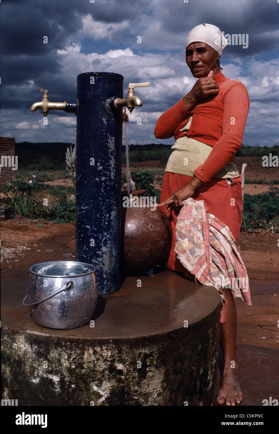 Eine Frau füllt Wassereimer an einem Brunnen in der Dürre vornübergeneigt Ost Region außerhalb von Fortaleza, Brasilien. Stockfoto