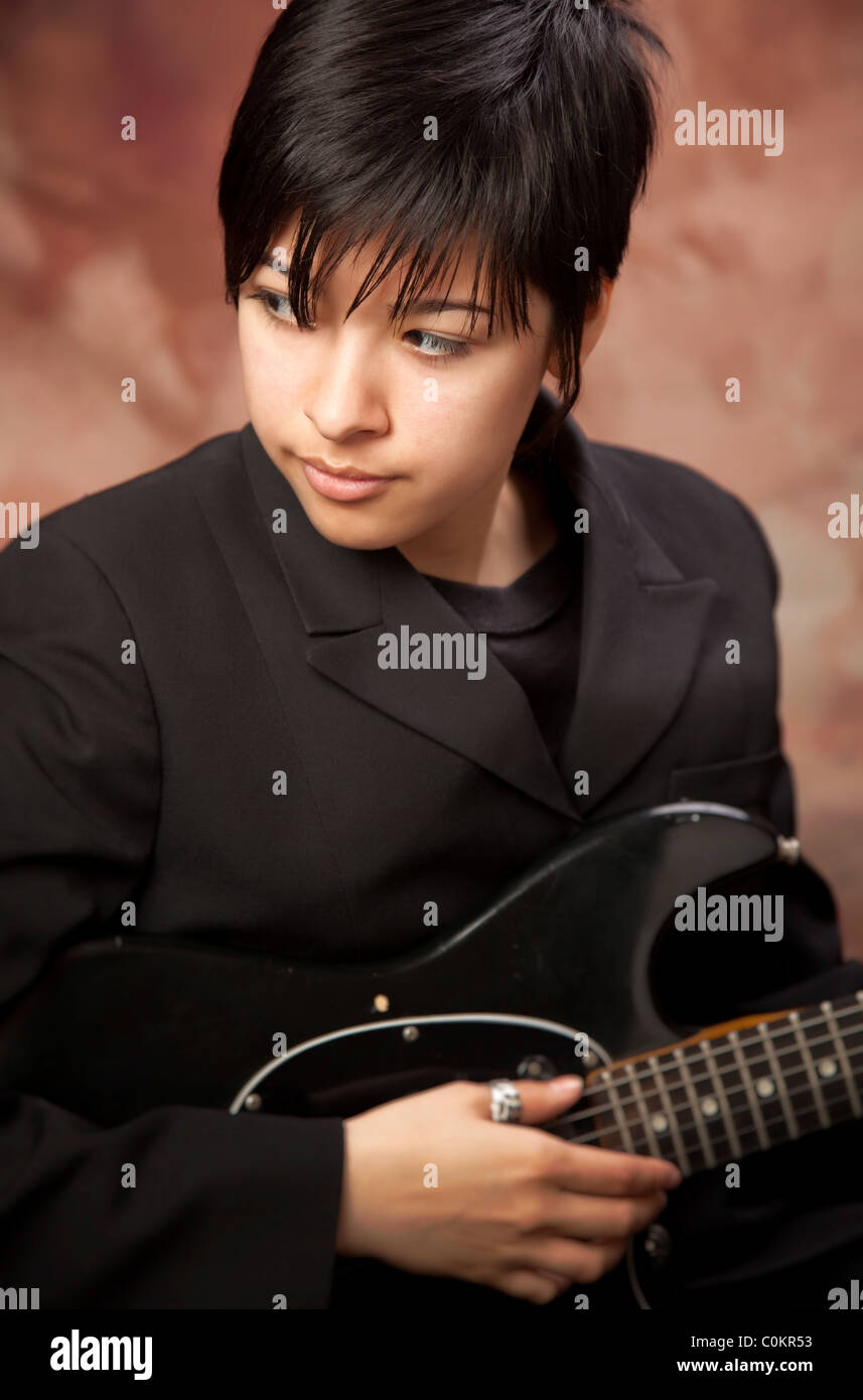 Gemischte Rassen Mädchen posiert für ein Muslin Hintergrund Porträt mit ihrer e-Gitarre. Stockfoto