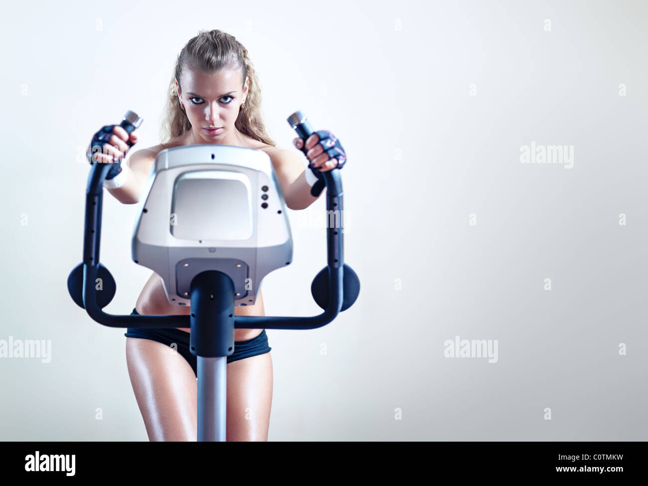 Junge Frau am Ergometer auf Wand Hintergrund. Stockfoto