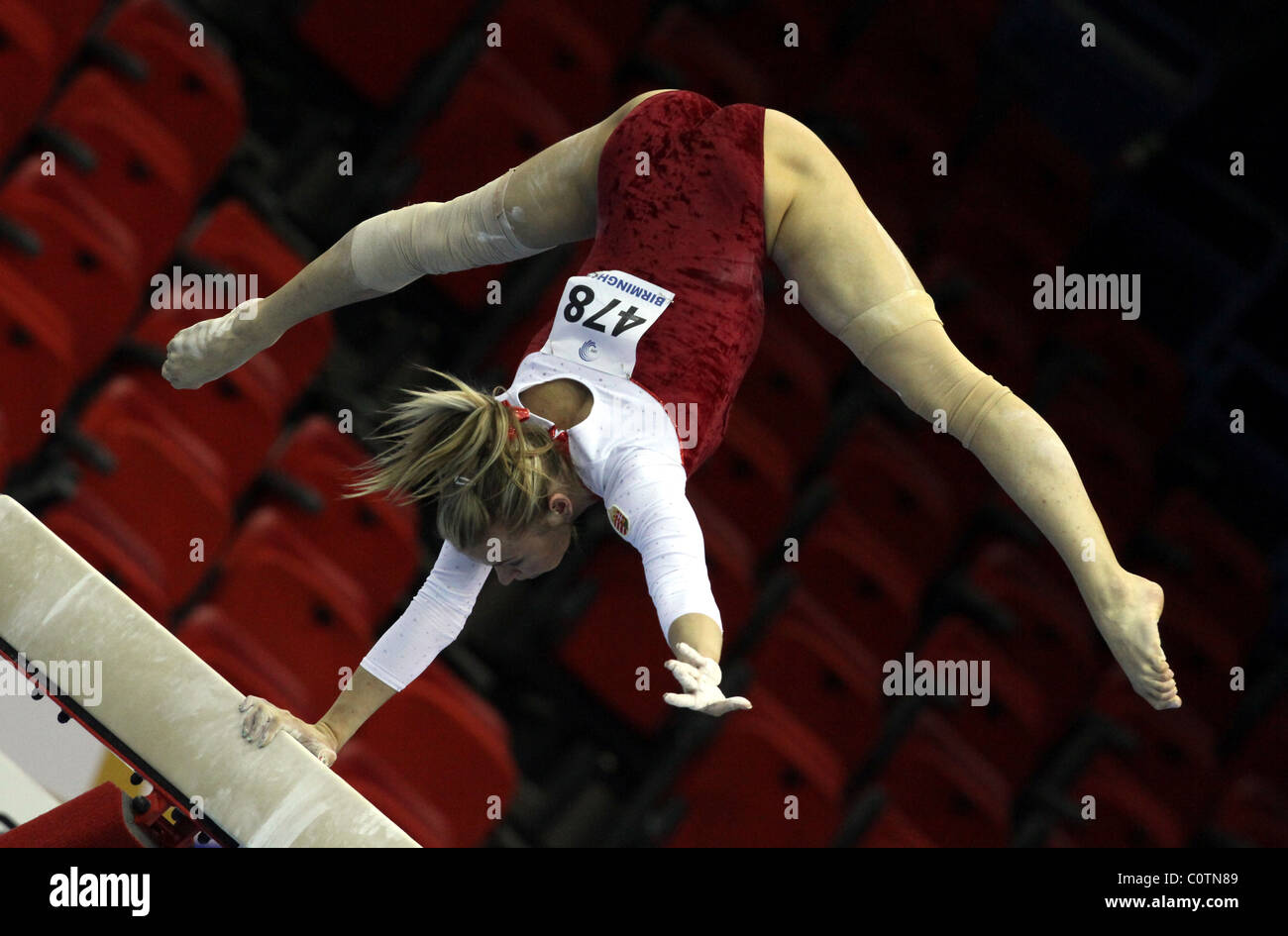 Weiblicher Gymnast führt einen Handstand mit nur einem Arm am Balken bei einem Gymnastik-Wettbewerb Stockfoto
