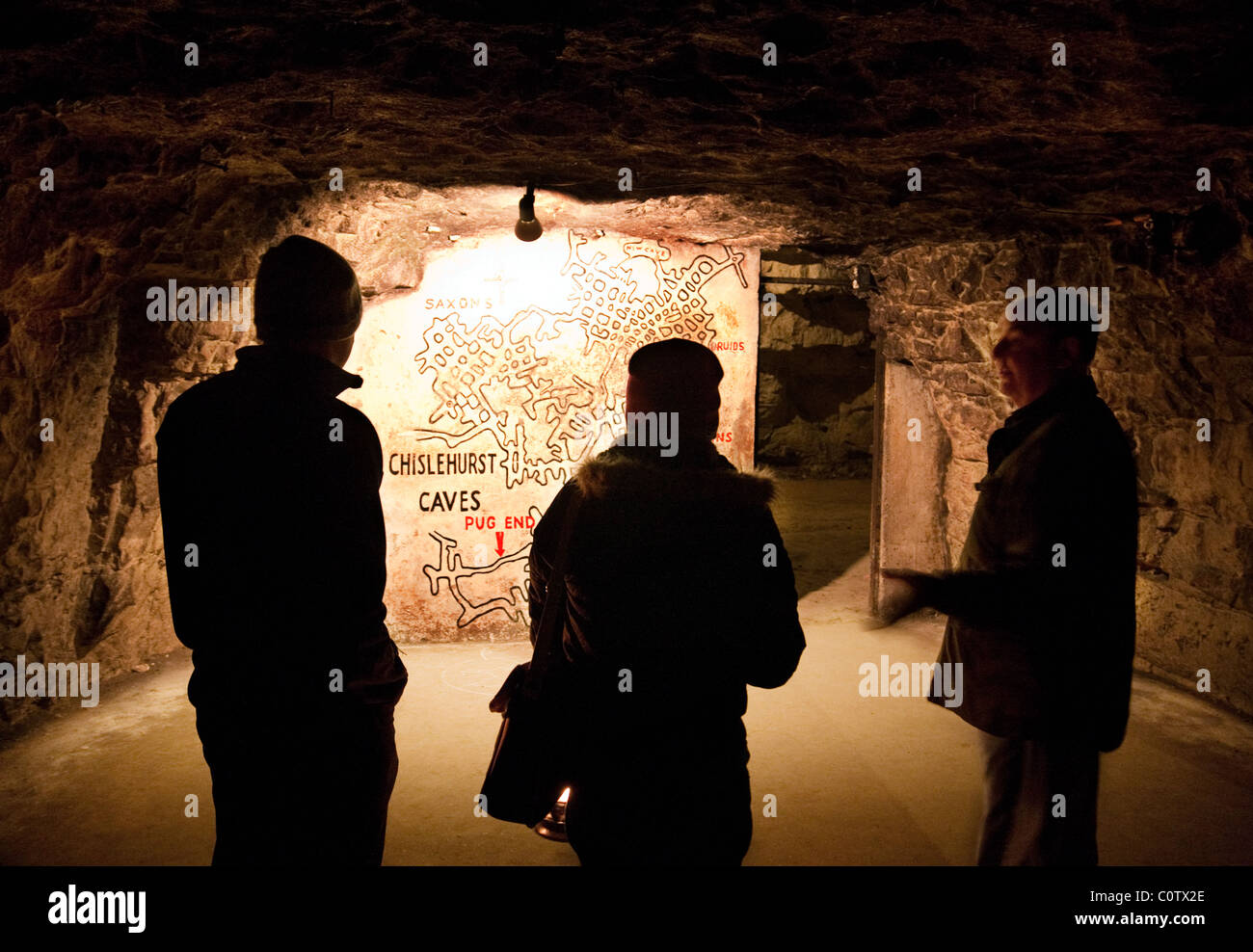 Zwei Personen und Reiseleiter auf einer Tour durch die Höhlen werden von ihrem Guide eine Karte gezeigt; Chislehurst Caves, Chislehurst, Kent, UK Stockfoto