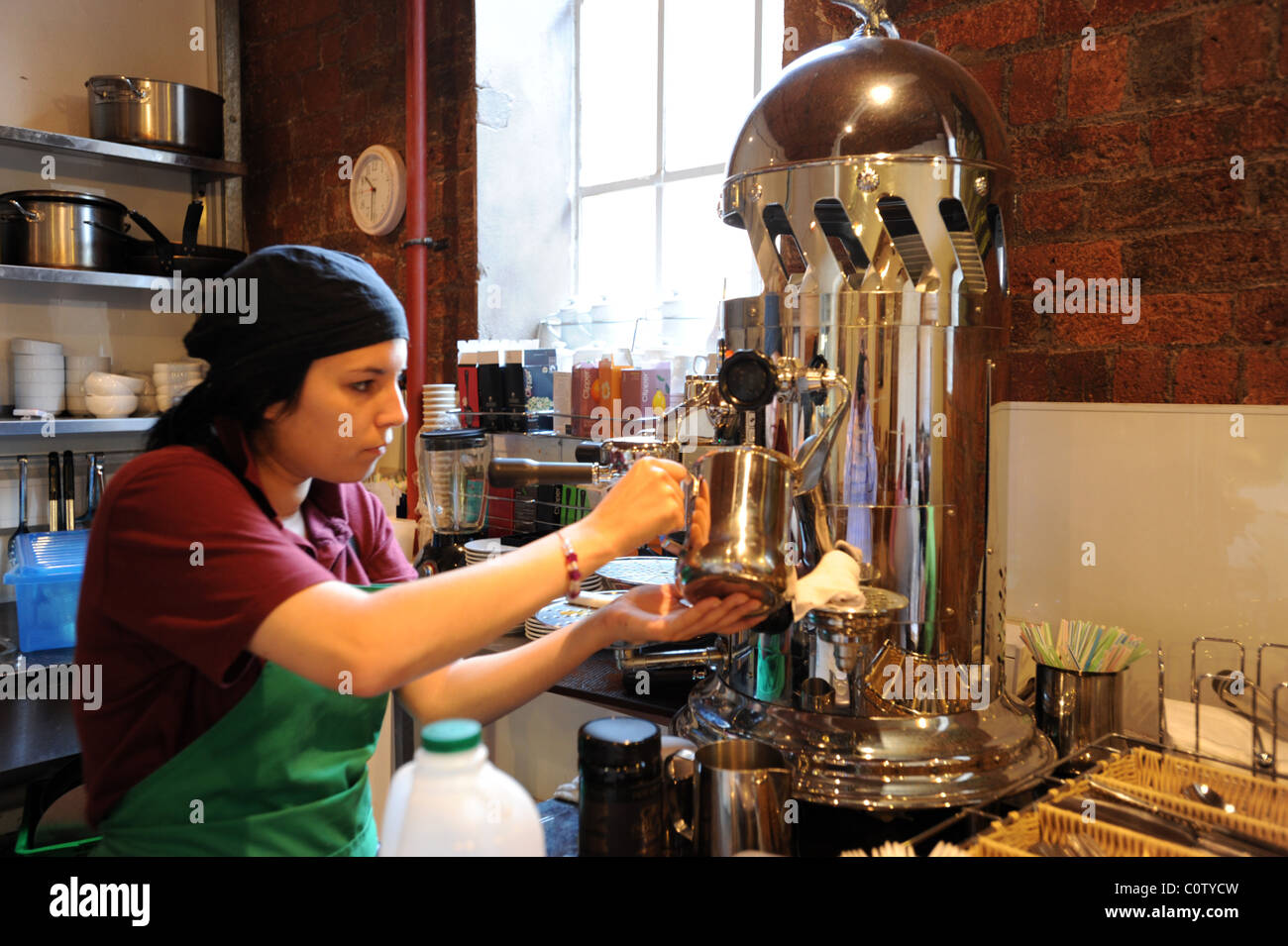 Junge weibliche Barista Aufschäumen auf eine exotische Espresso-Maschine Stockfoto