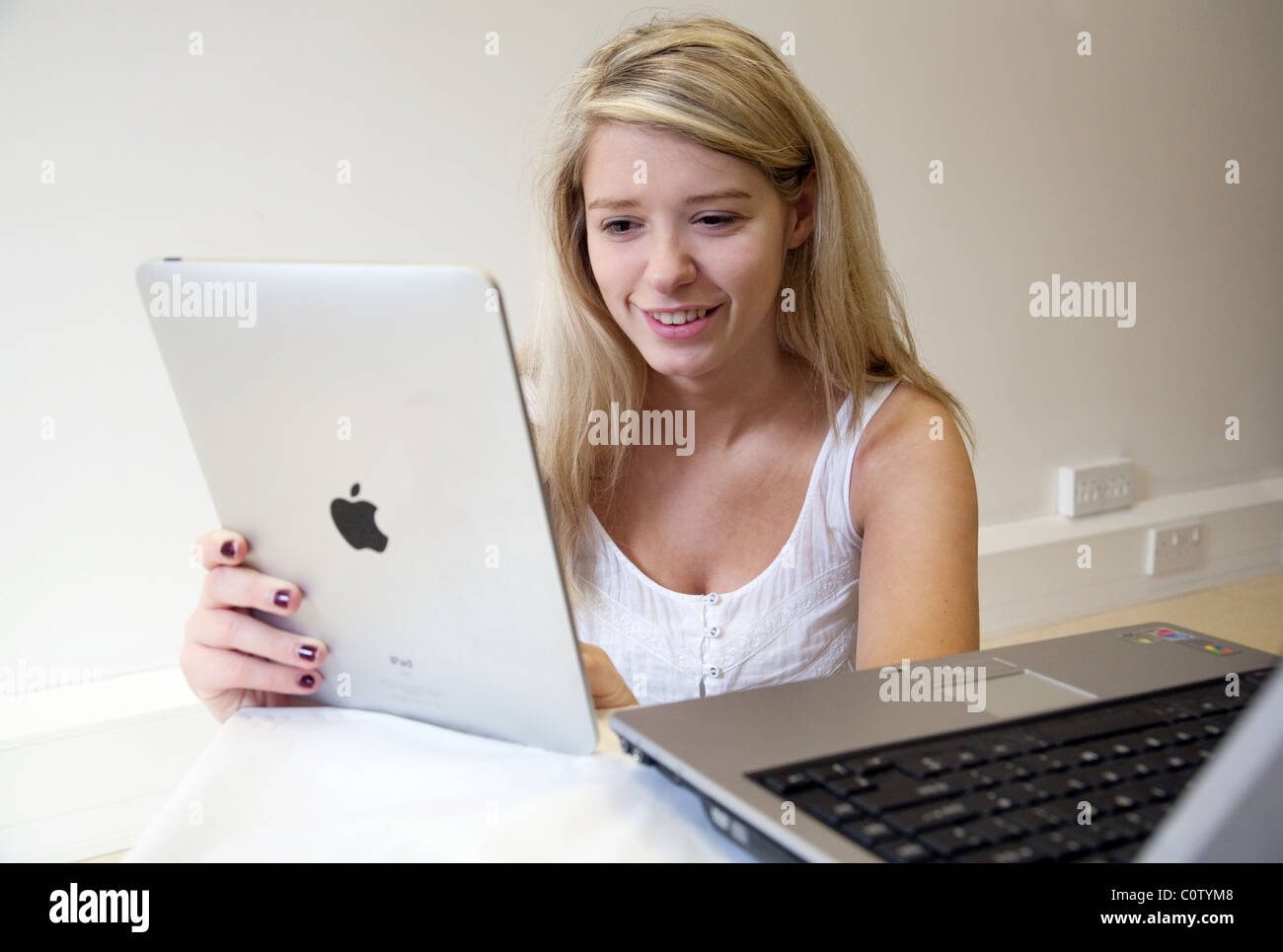 Blondes junges Mädchen hält Apple Ipad und auch mit Laptop-computer Stockfoto