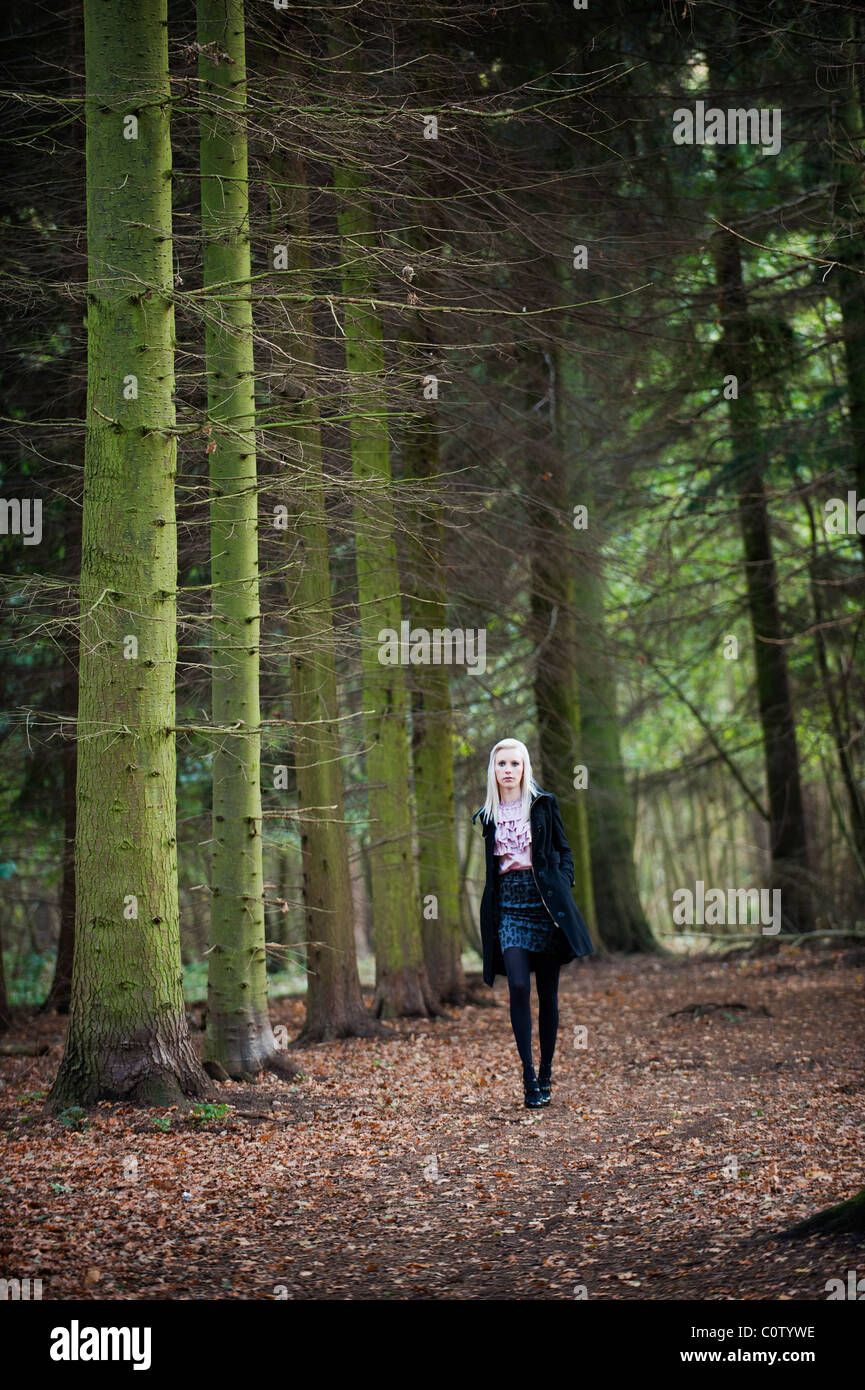 junges blonde Modell in Minirock und geraffte Bluse allein zu Fuß durch Wald im Herbst fallen Stockfoto