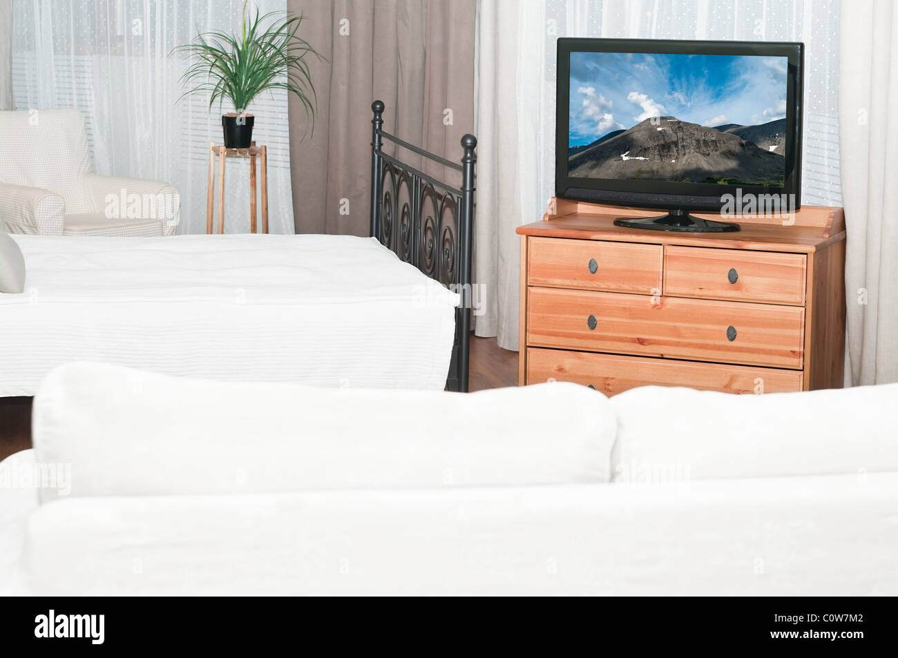 Den großen Fernseher in einem Raum vor einem weißen Sofa. Ein Schlafzimmer mit einem Bett Stockfoto