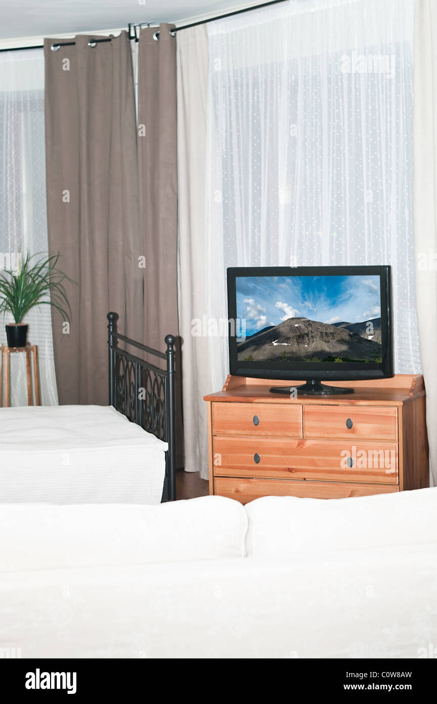 Den großen Fernseher in einem Raum vor einem weißen Sofa. Ein Schlafzimmer mit einem Bett Stockfoto