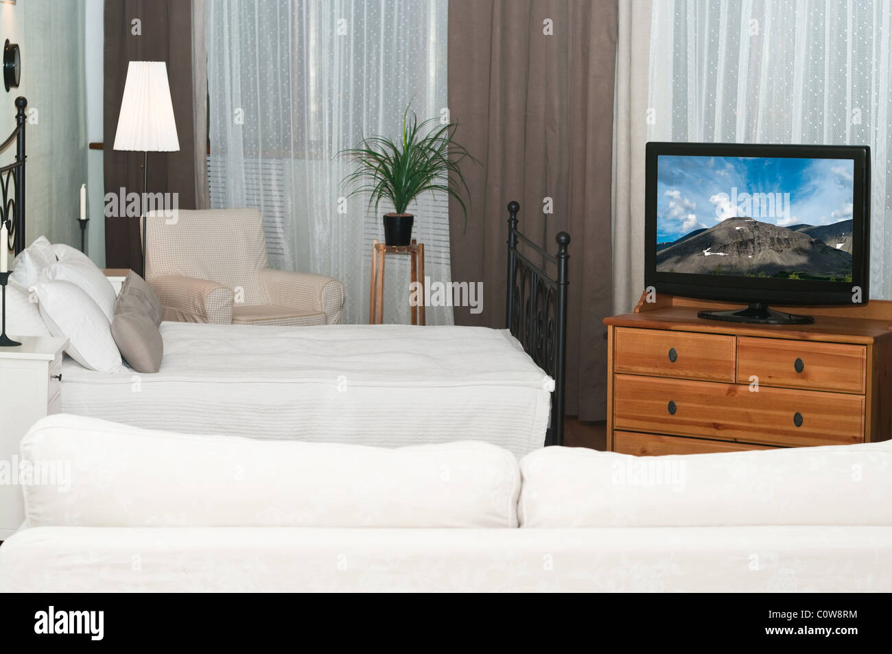 Der große Fernseher in einem Raum vor einem weißen Sofa. Ein Schlafzimmer mit einem Bett Stockfoto