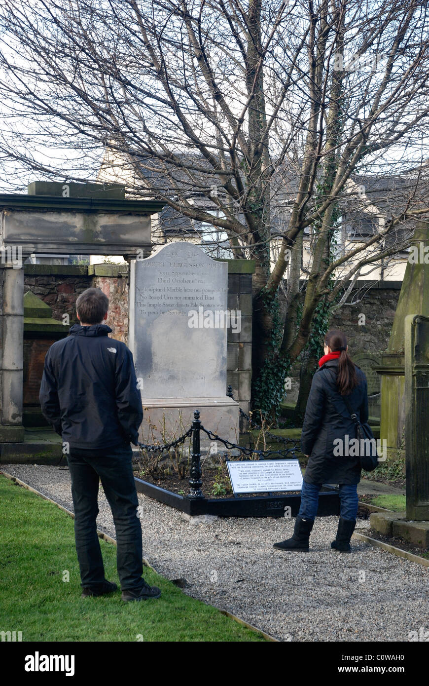 Ein paar besuchen das Grab des schottischen Dichters Robert Fergusson im Canongate Kirkyard, Edinburgh. Stockfoto