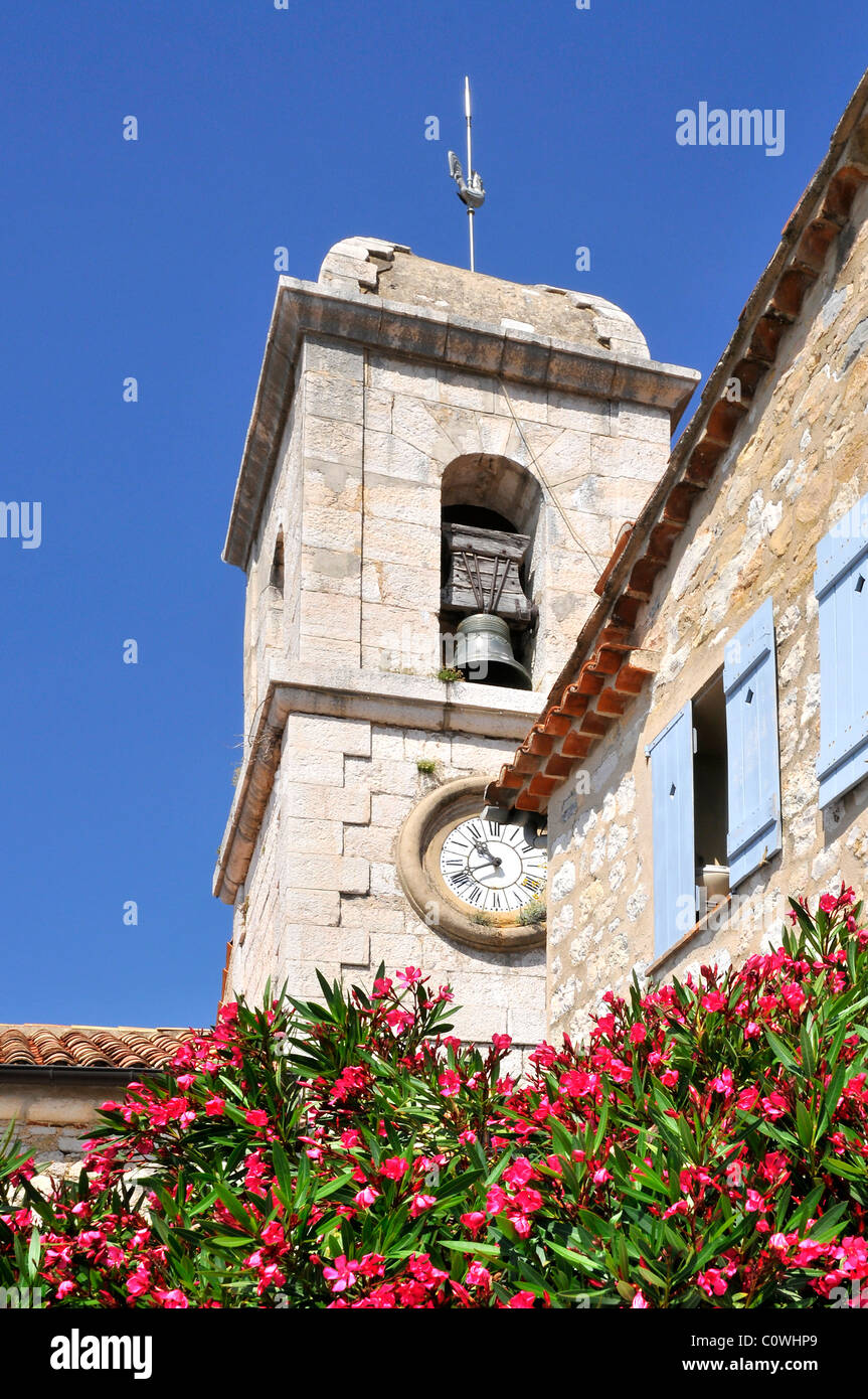 Glockenturm der Kirche Saint-Vincent von Gourdon in Frankreich mit Nerium Oleander Blume im Vordergrund. Alpes-Maritimes Stockfoto