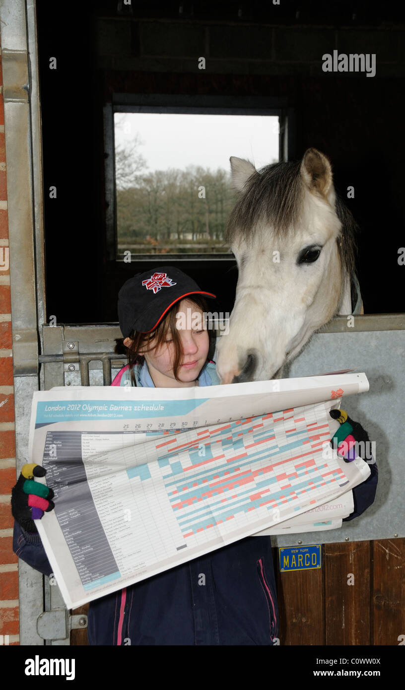 Kleines Mädchen mit einem London Olympia Mütze Blick durch den Spielplan mit ihrem Haustier pony Stockfoto