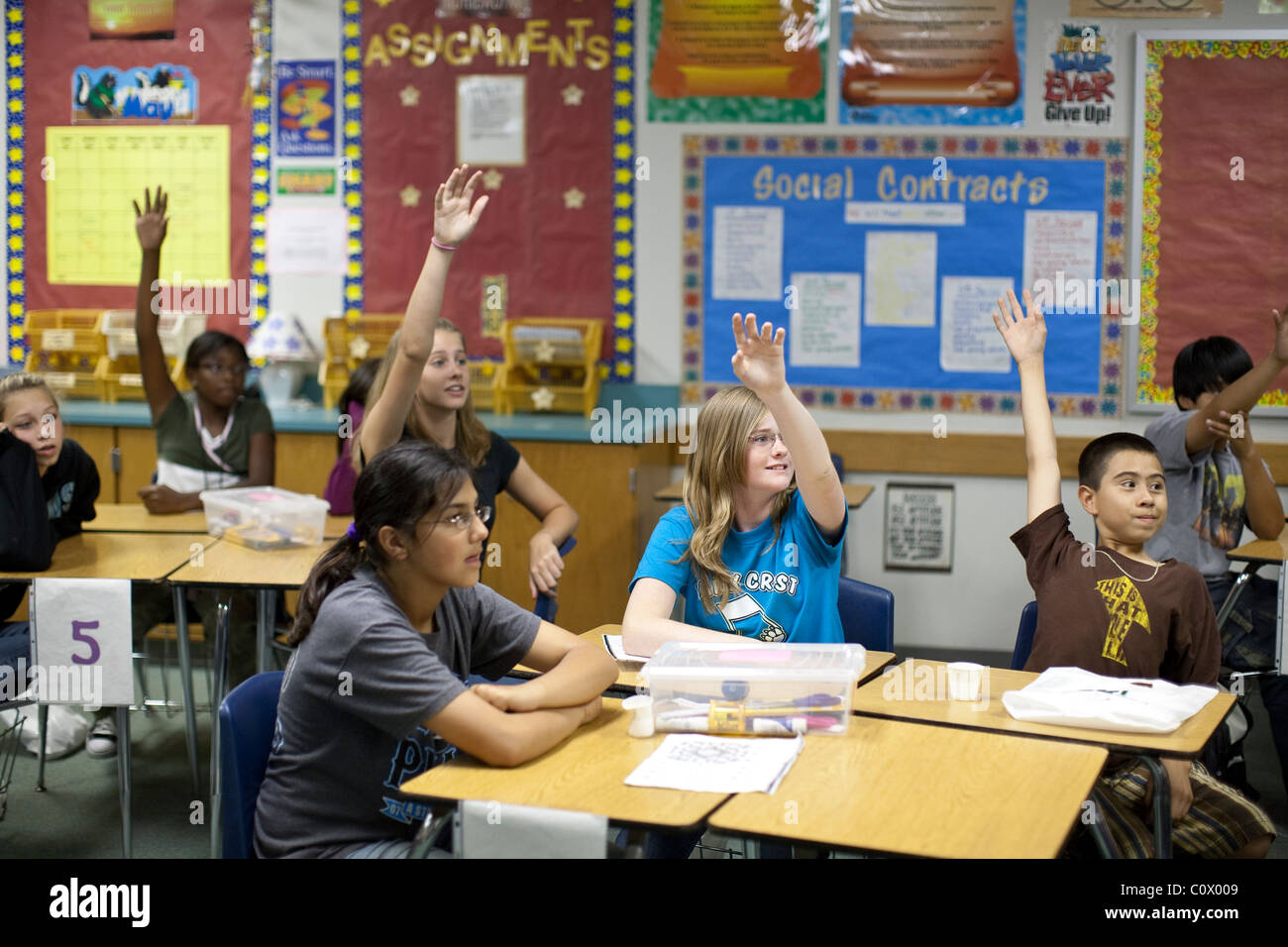 Ethnisch gemischten Gruppe von Mittelschüler / innen in Sozialkunde Klasse heben die Hände des Lehrers Frage beantworten Stockfoto