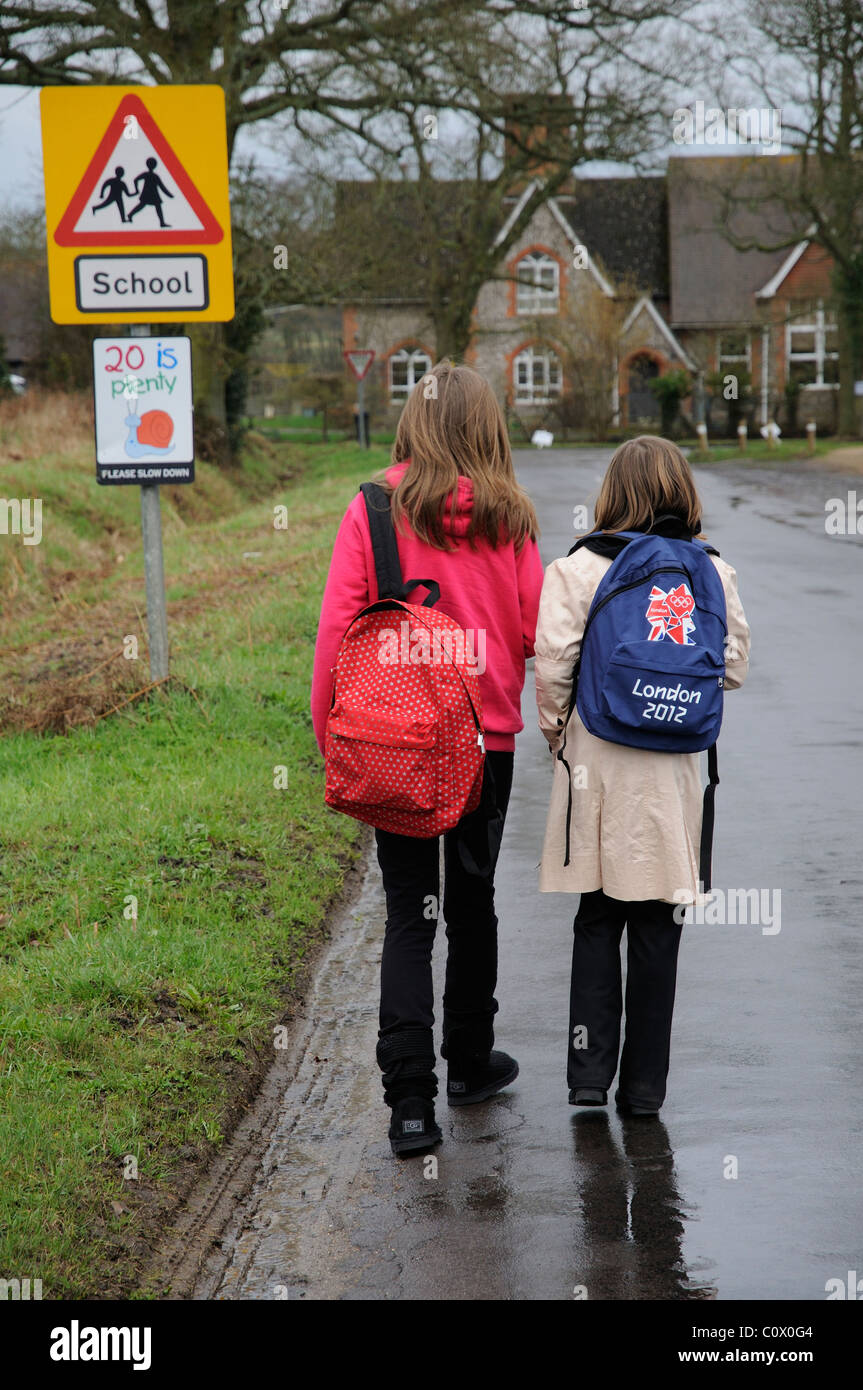 Schülerinnen und Schüler zu Fuß zur Schule entlang einer Landstraße ohne Pflaster oder Gehweg Hampshire England UK Stockfoto
